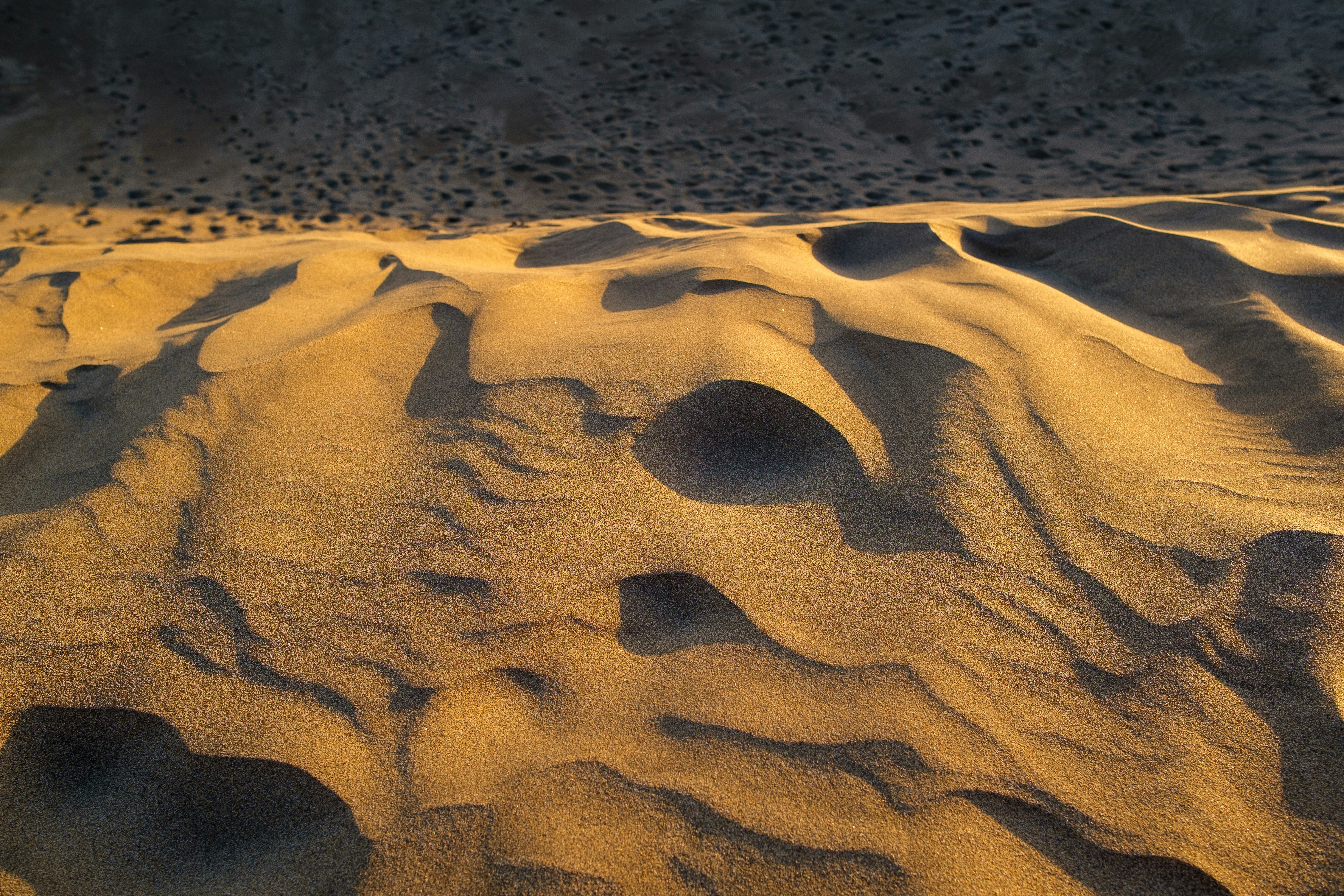 Golden sand dunes with rippling textures at sunset.