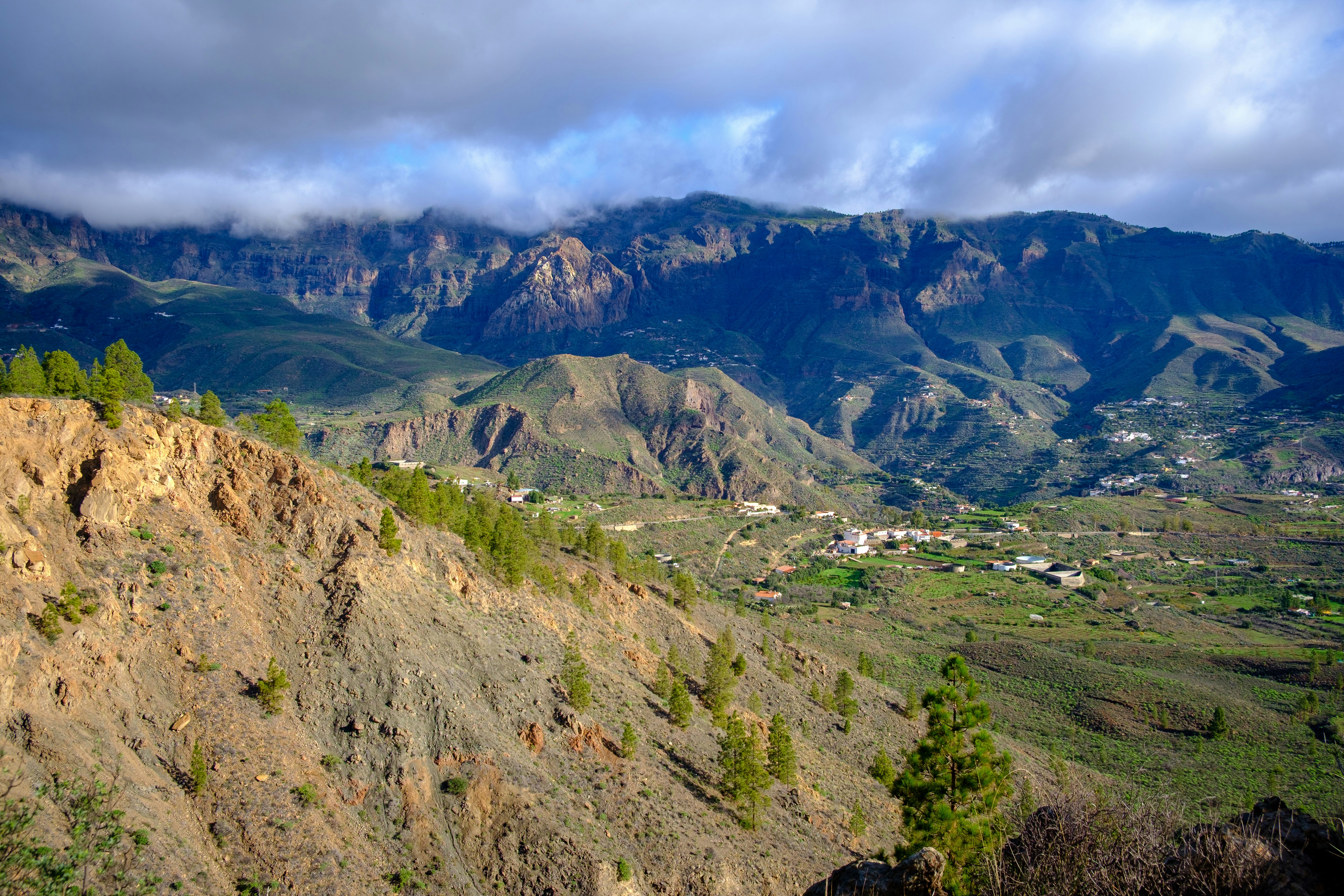 Rocky mountains with green valley and scattered houses.