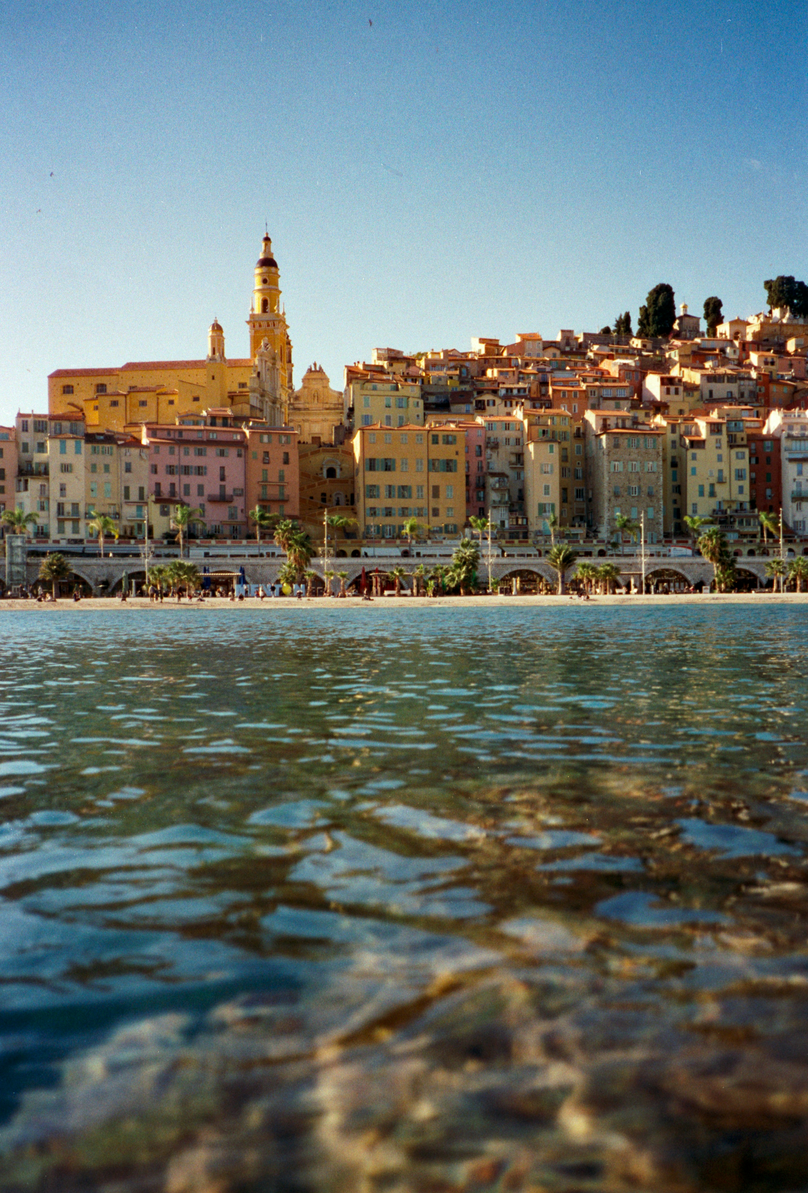 Bunte Gebäude säumen die Küste mit klarem Wasser im Vordergrund.