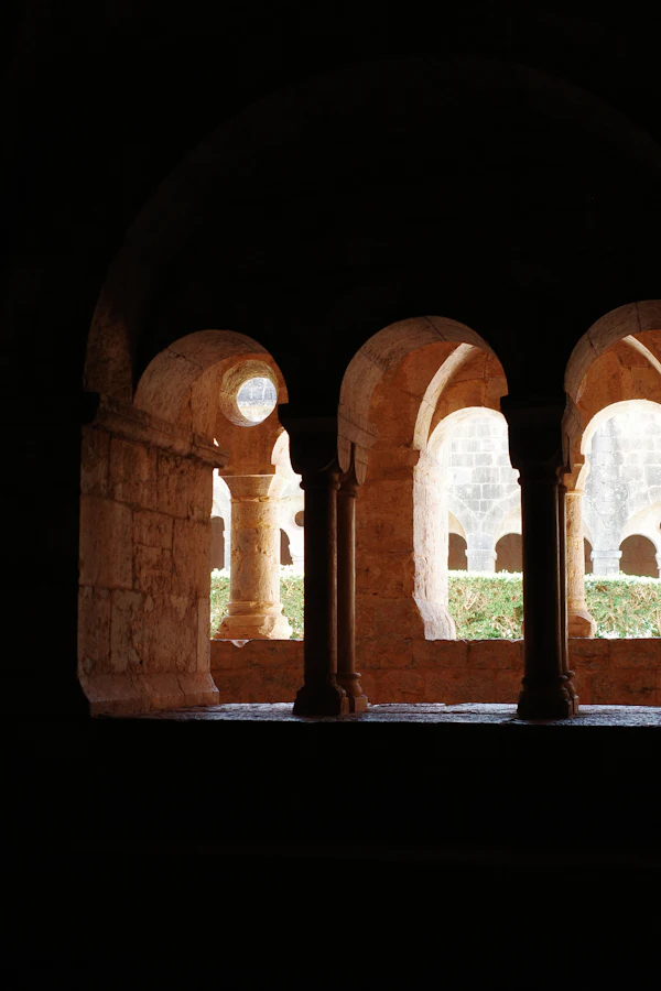 Sunlit stone arches and columns lining a church courtyard