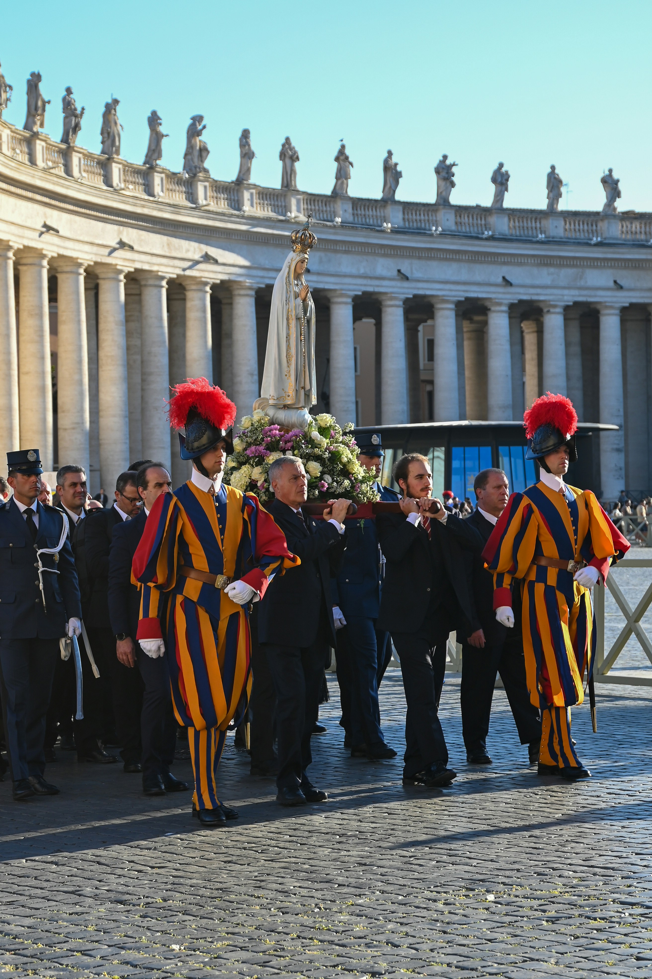 Swiss guards escorting a statue of mary in vatican city.