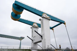 A blue and white drawbridge with yellow counterweights.