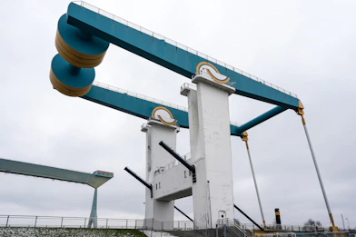 A blue and white drawbridge with yellow counterweights.