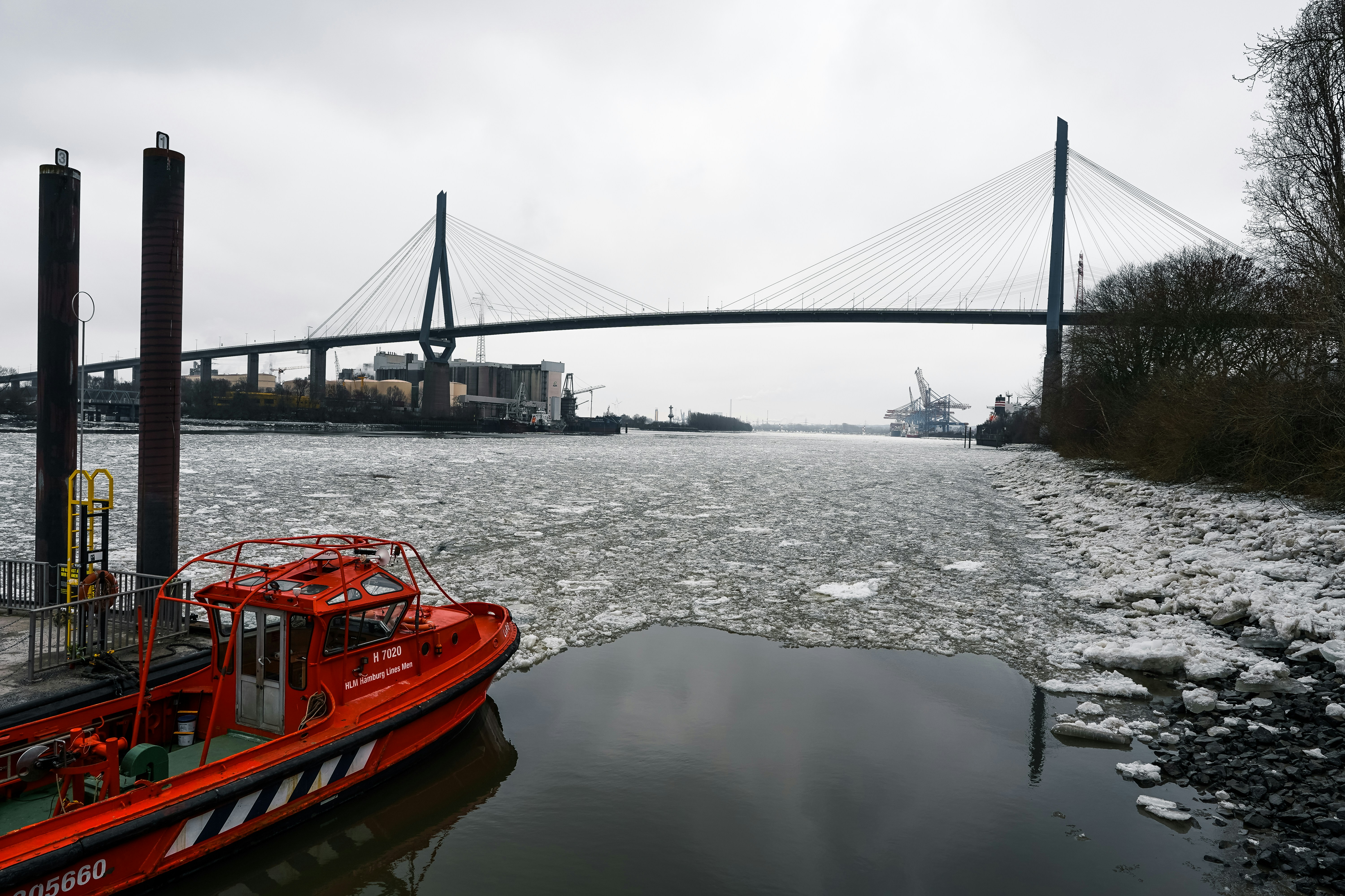 Red boat near a bridge with ice floes on water