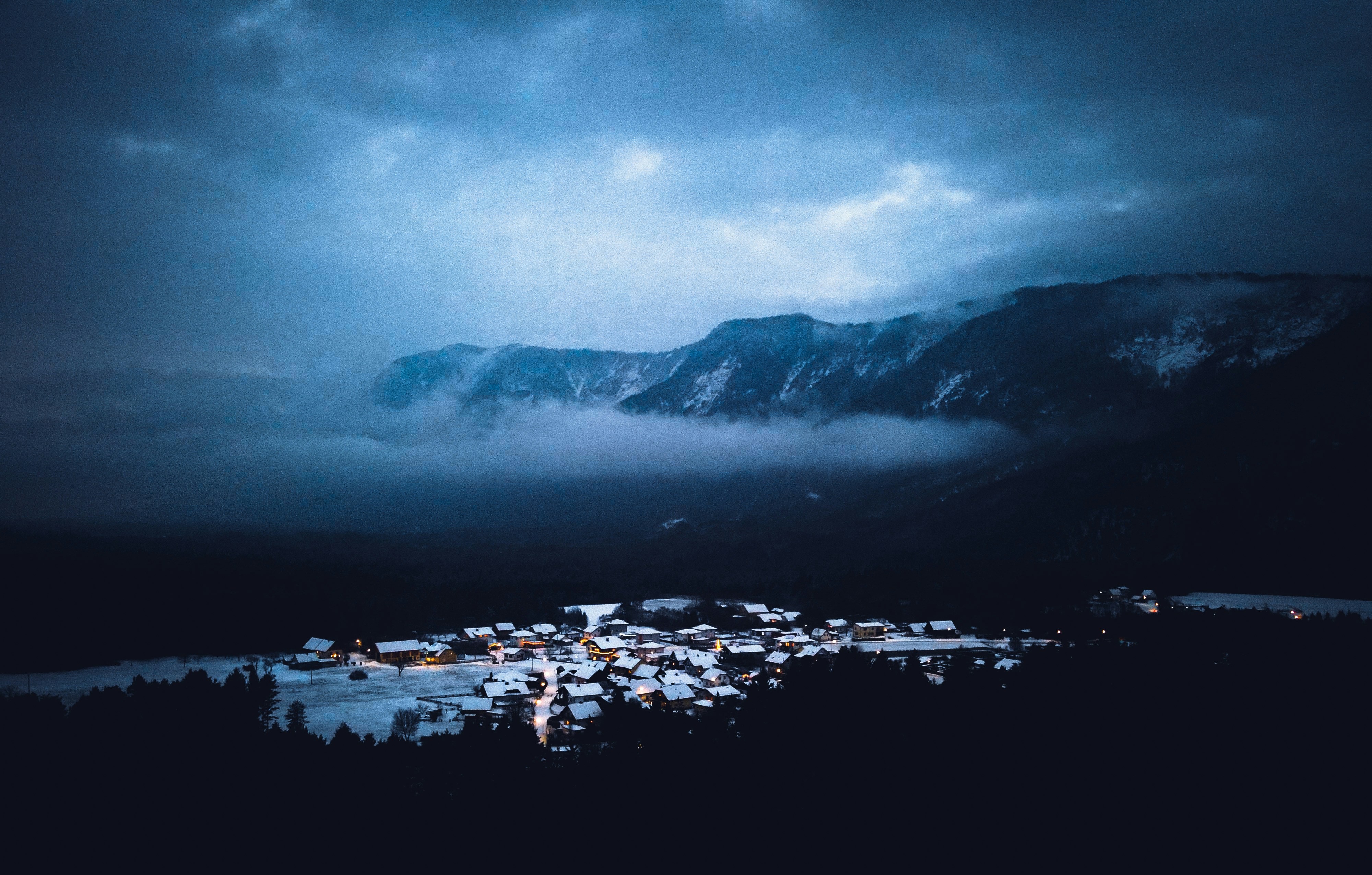 A small village glows at night under stormy skies.