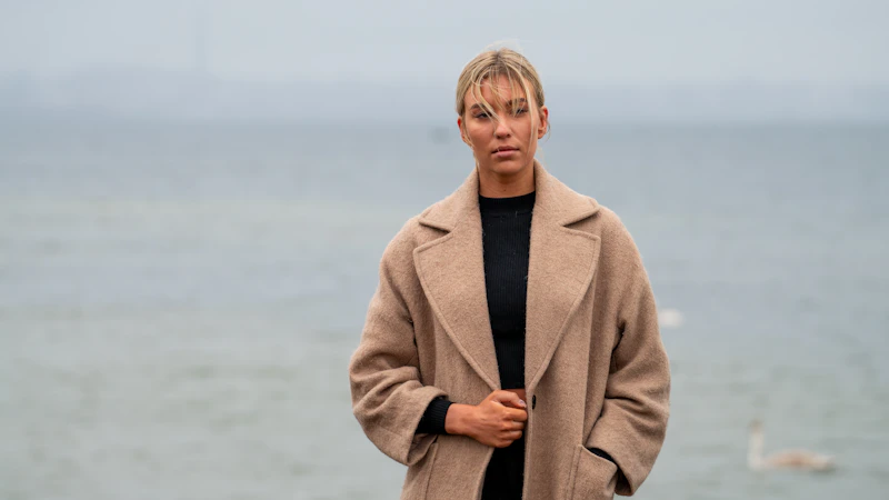 mujer elegante en abrigo beige junto al agua