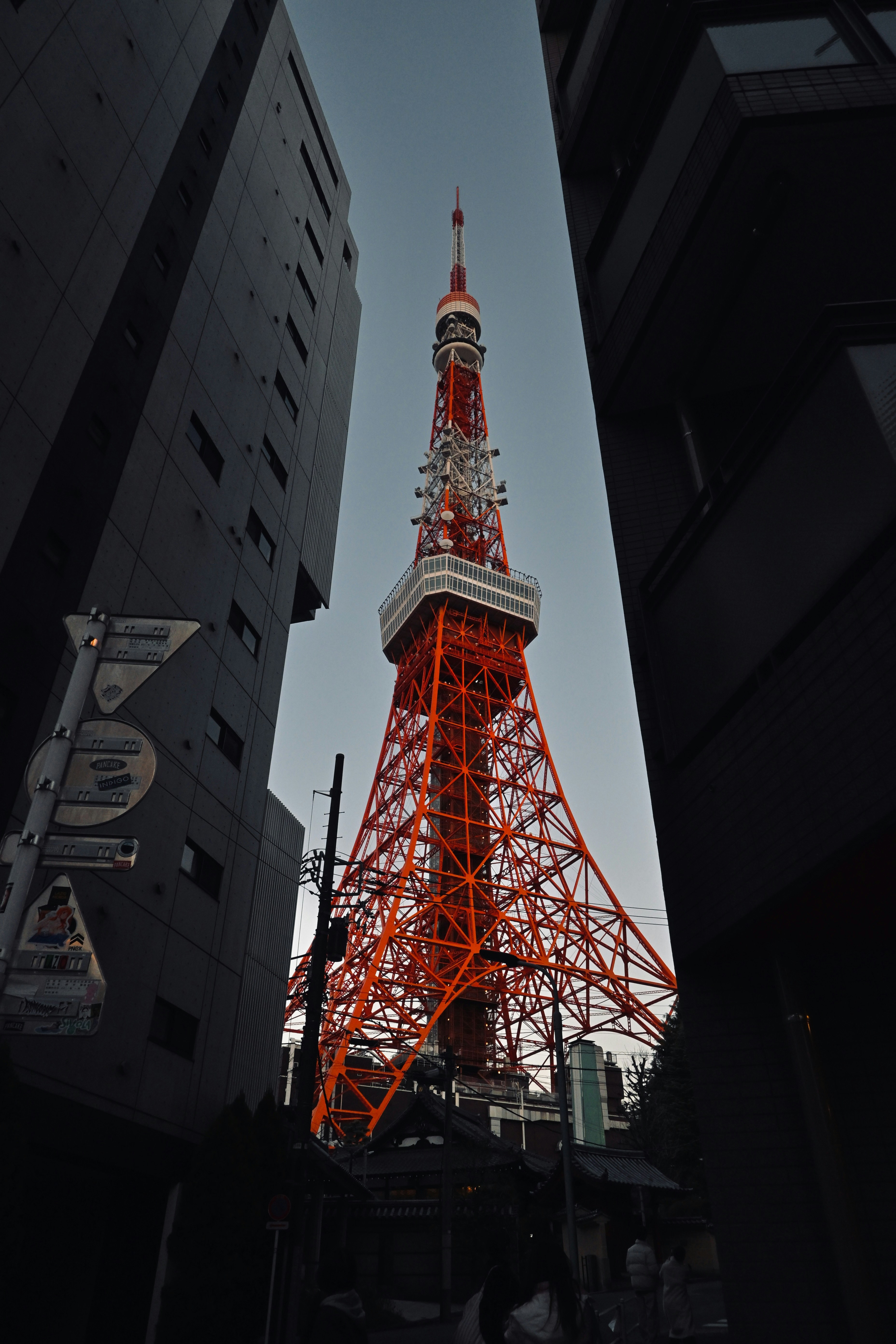 Tokyo tower illuminated red between tall buildings