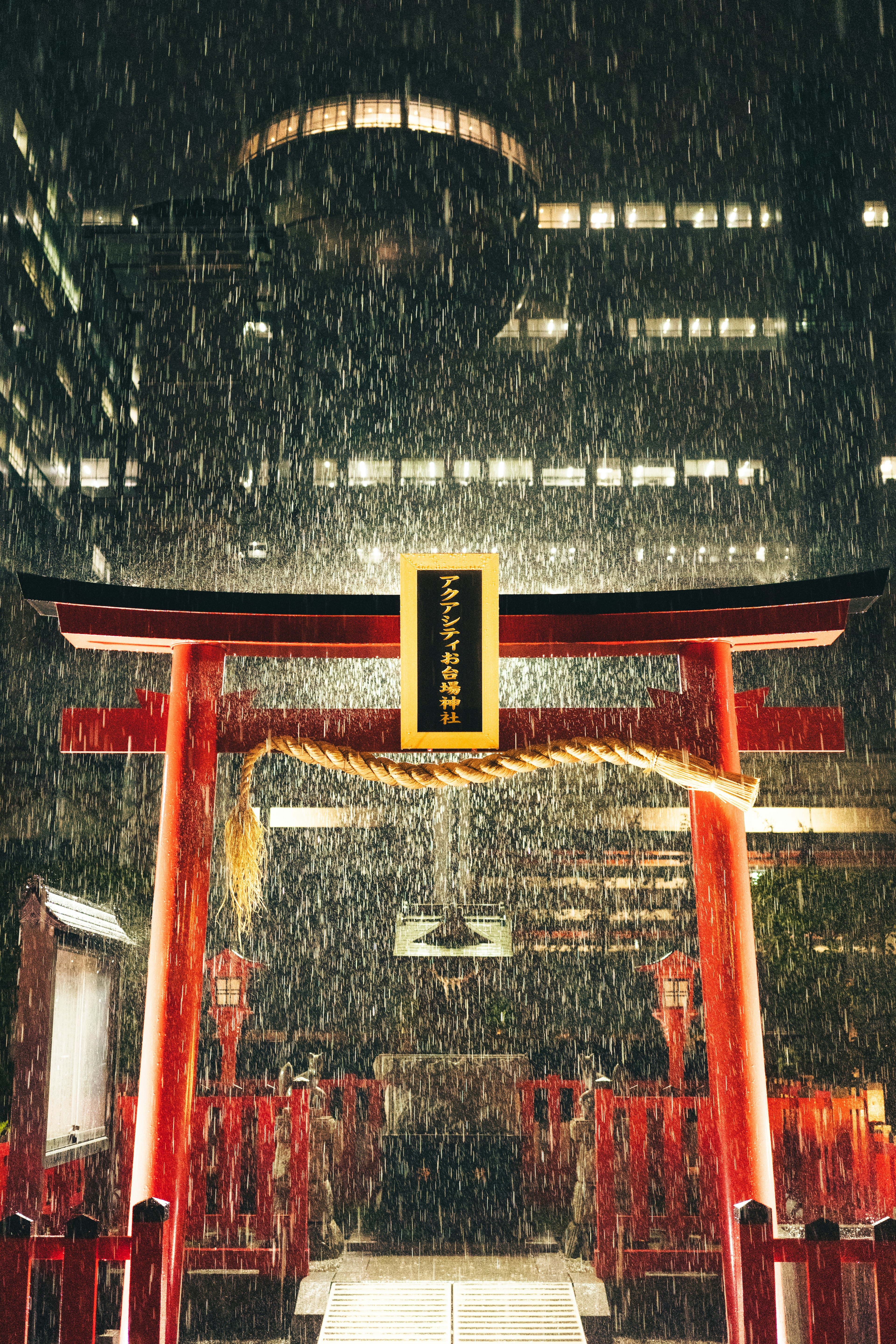 A red torii gate in the rain at night.