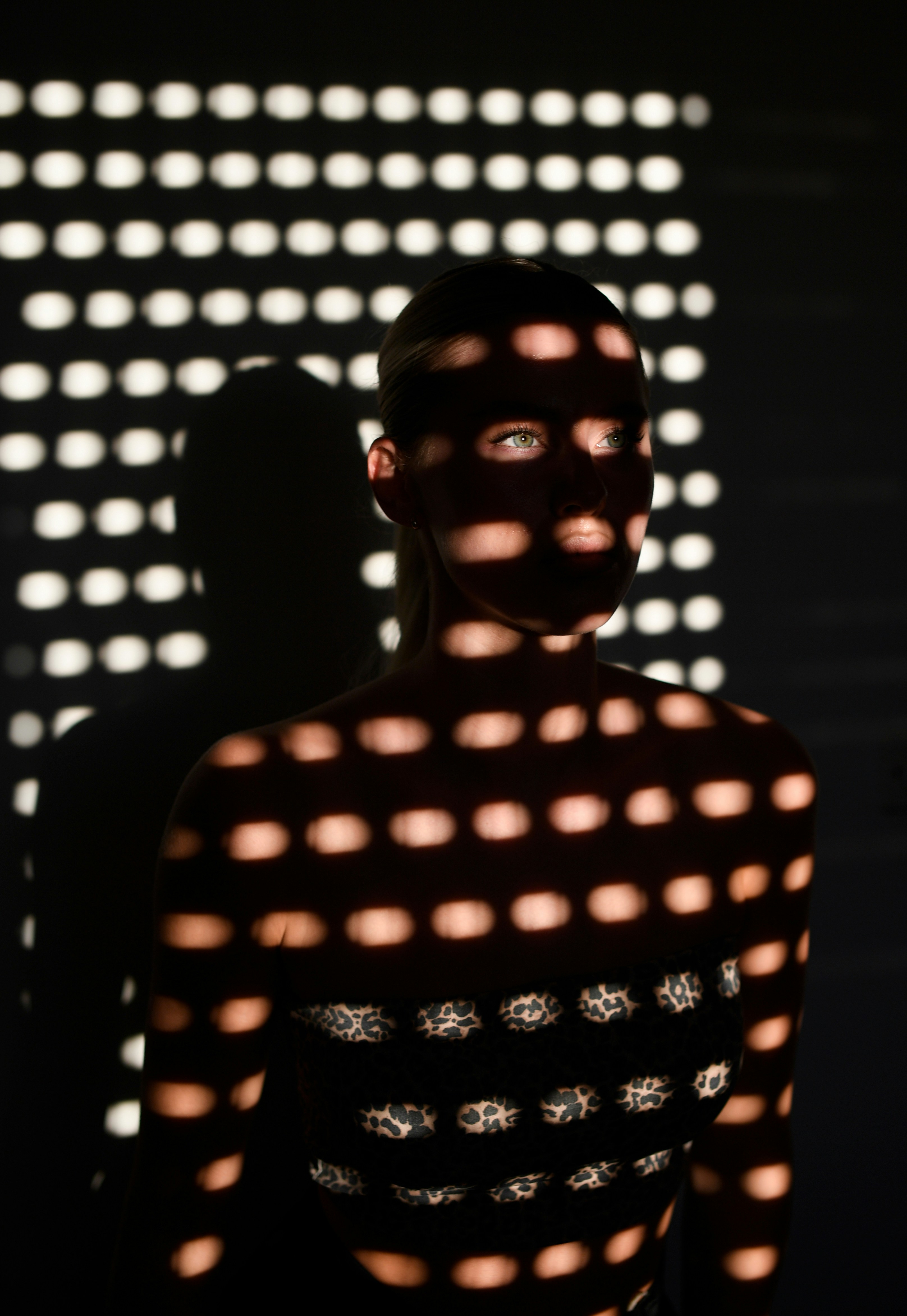 Person illuminated by patterned light and shadow