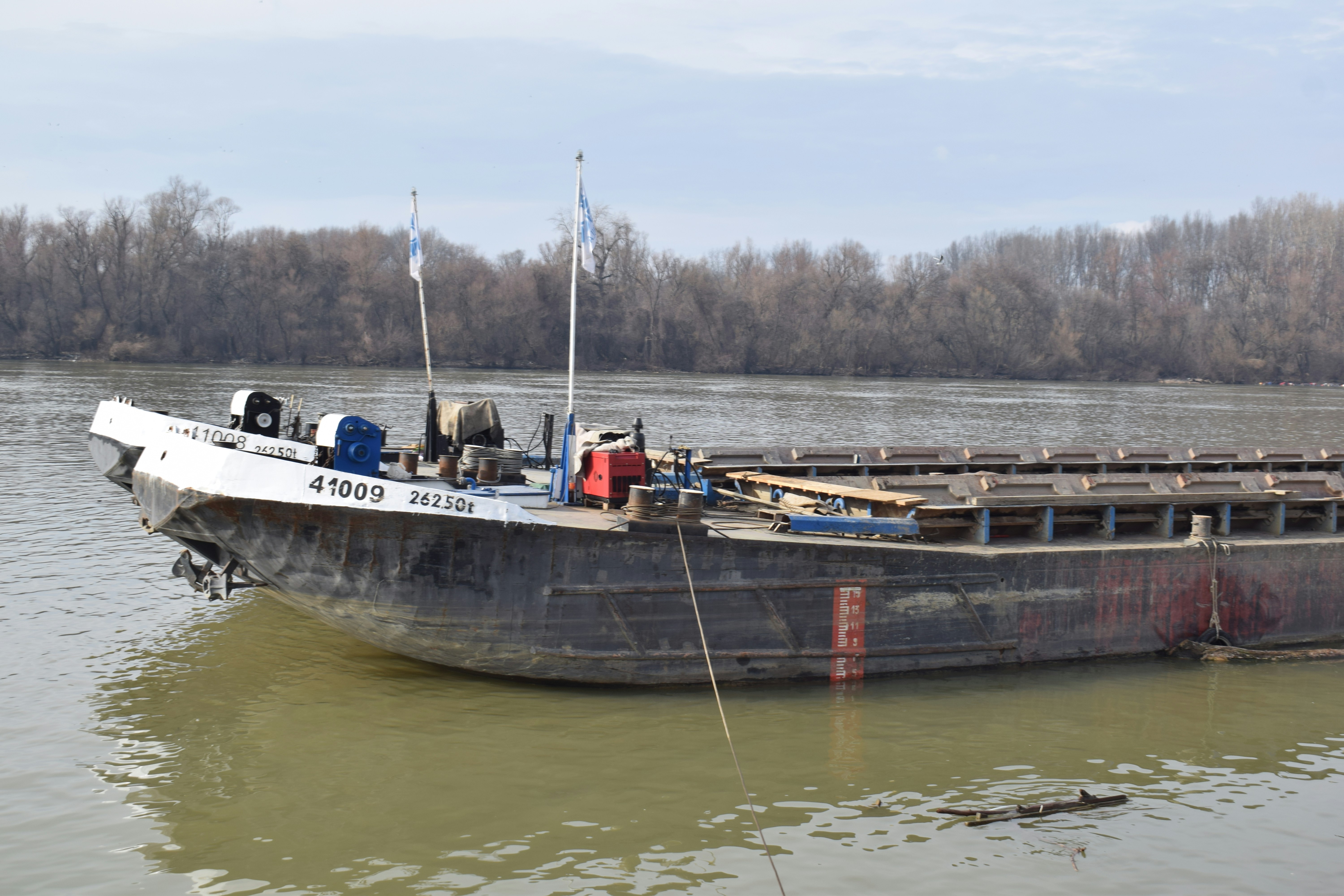 A barge floats on a murky river near trees