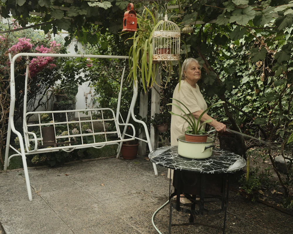 An older woman watering plants in her garden