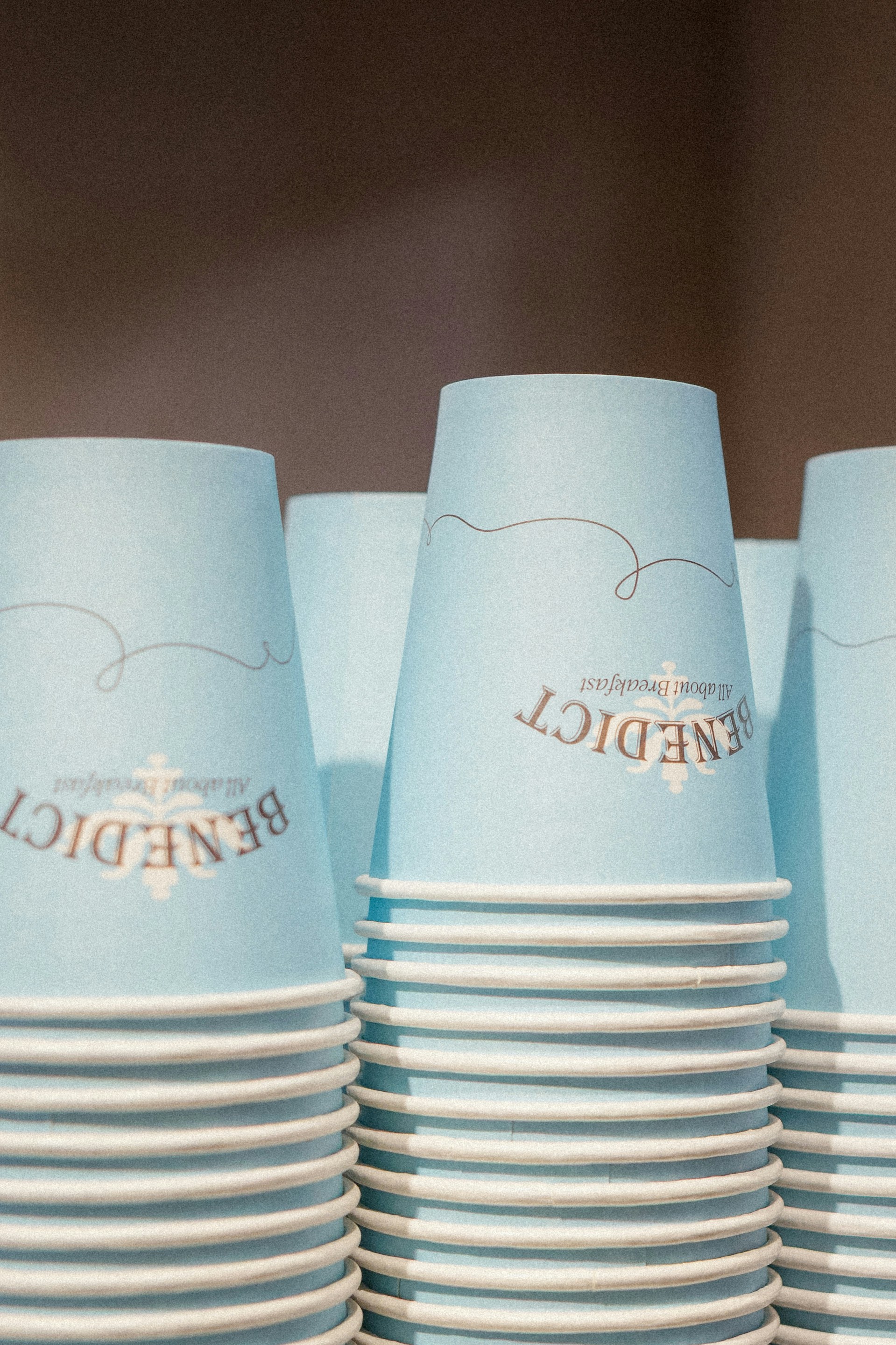 Stapel hellblauer Pappbecher mit Branding.