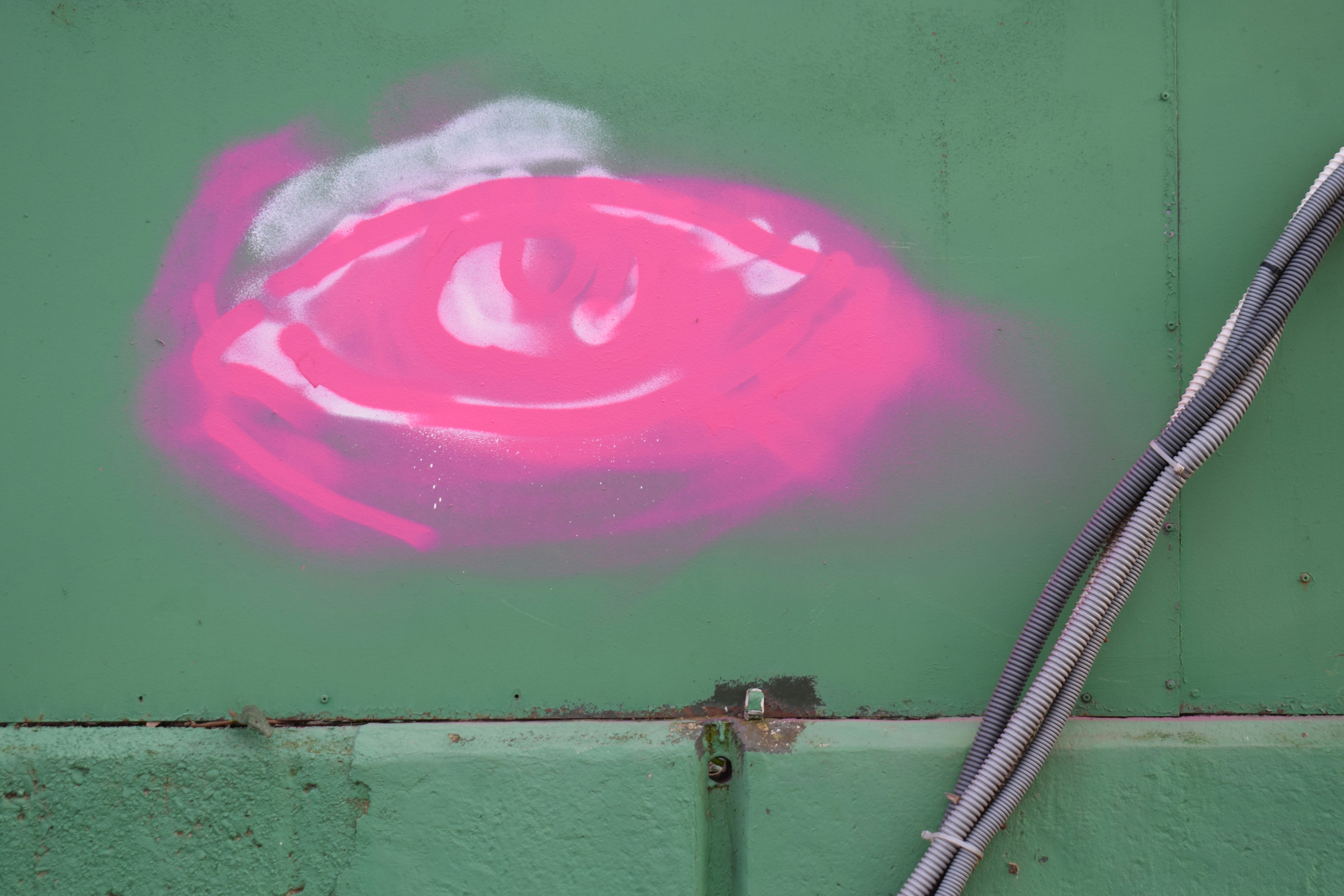Pink spray paint on a green metal surface.