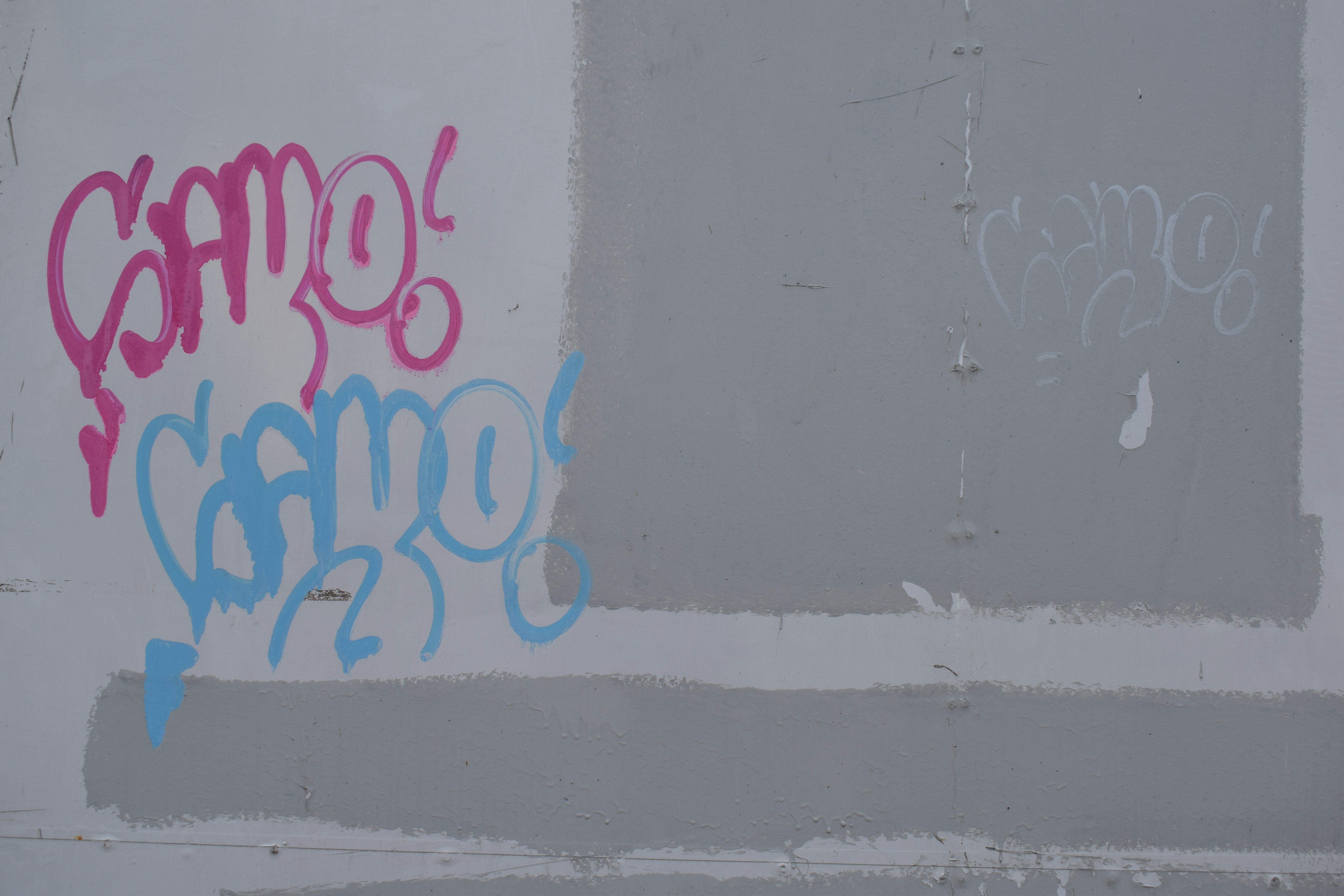 Pink and blue graffiti on a grey wall