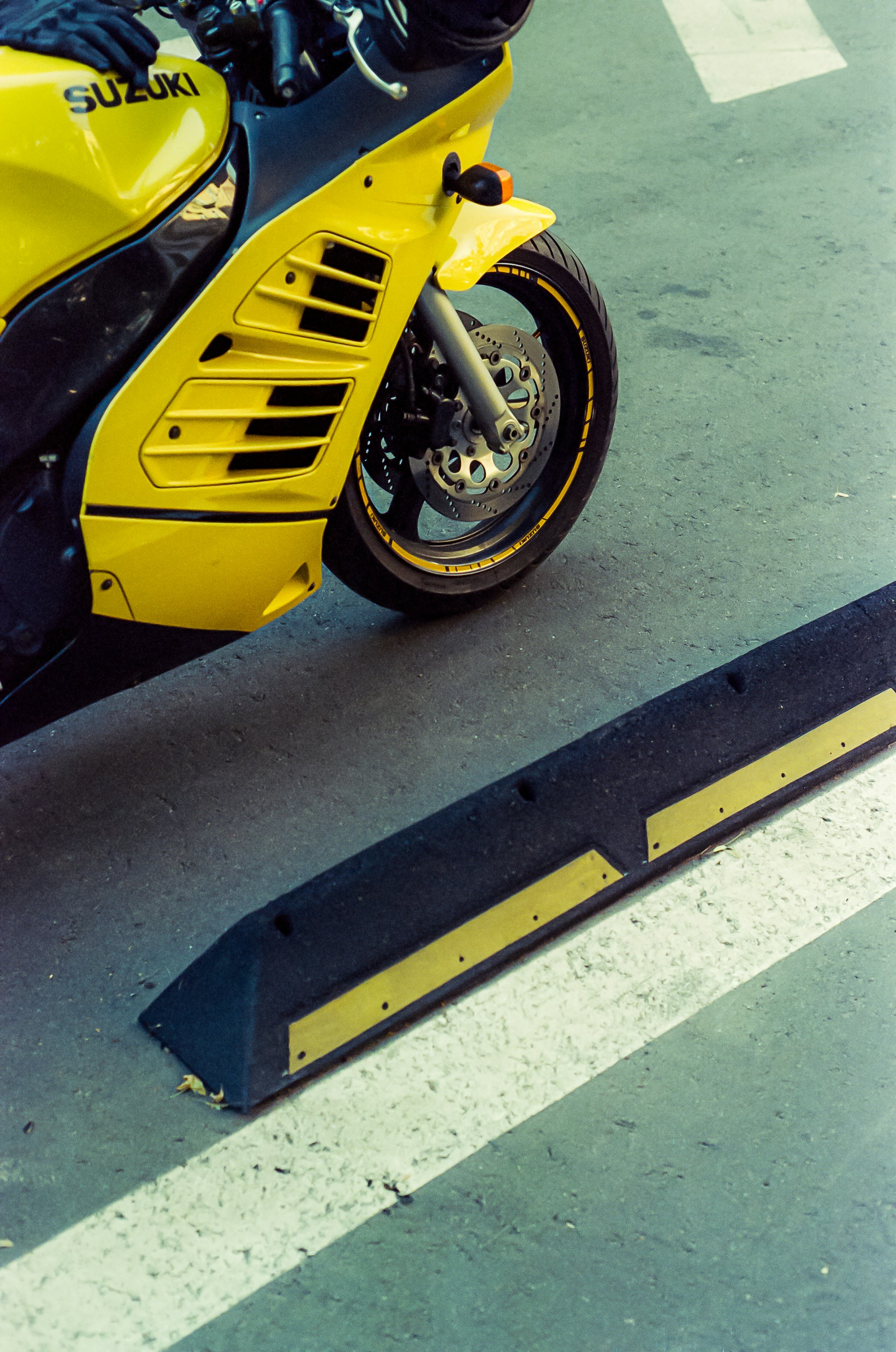 A bright yellow suzuki motorcycle parked on pavement.