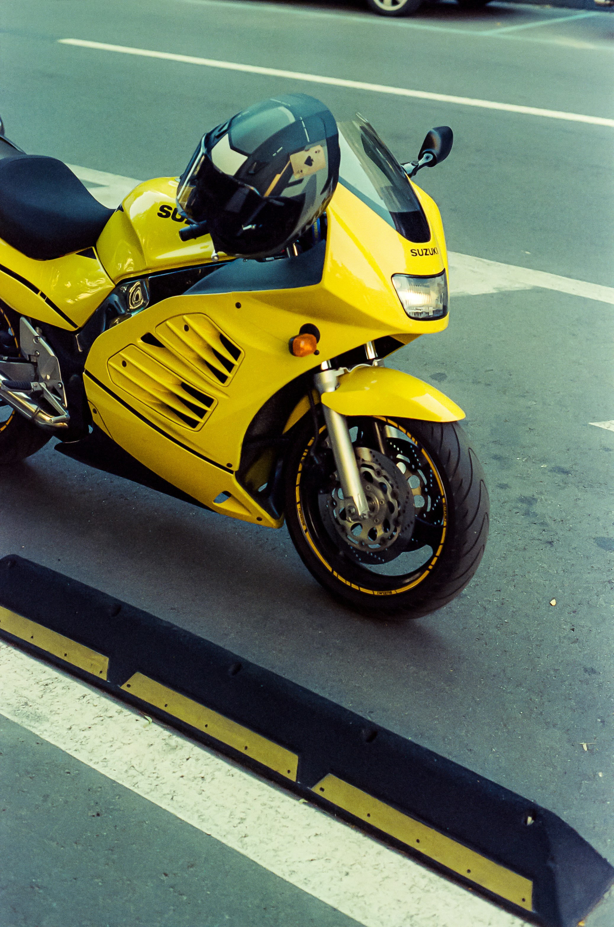 A bright yellow motorcycle with a helmet on the seat.