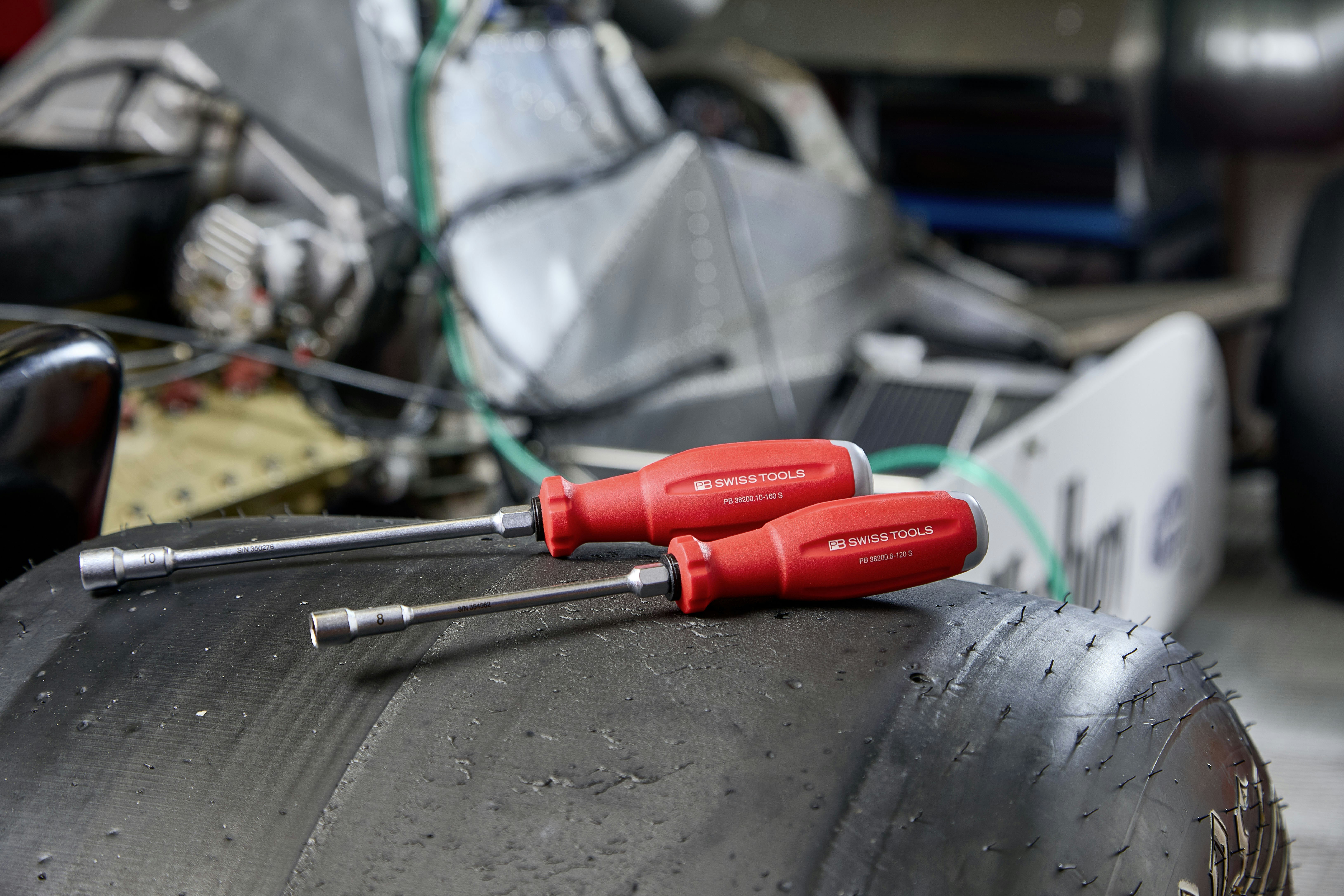 Two red screwdrivers resting on a tire.