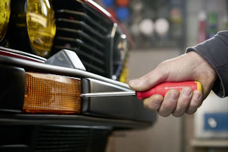 Hand using screwdriver to fix car bumper