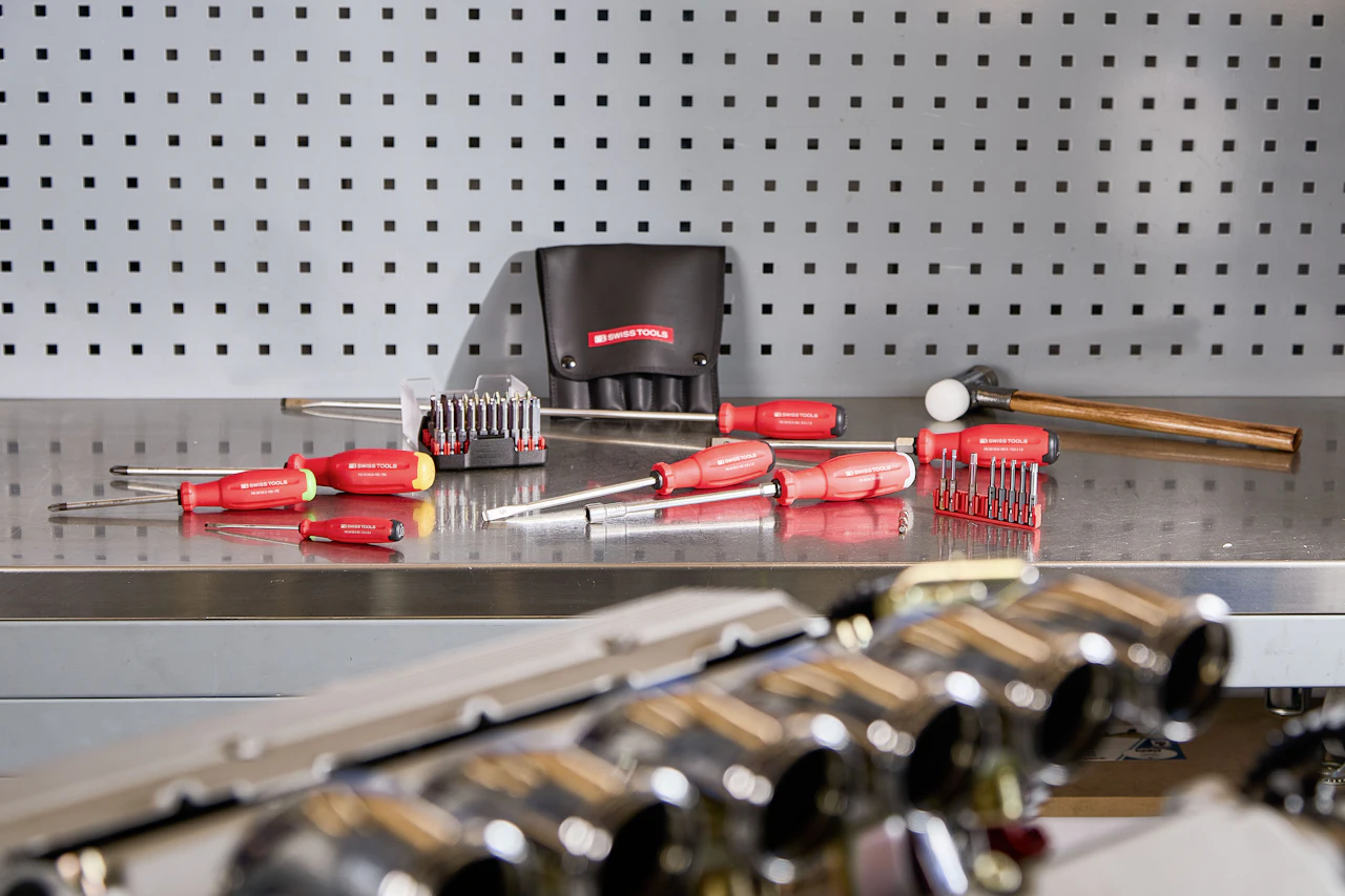 Screwdrivers and hand tools laid out on a steel workbench