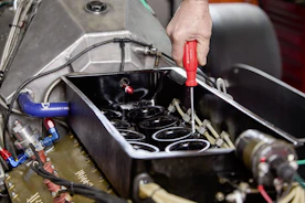 Mechanic using a screwdriver on car engine parts.