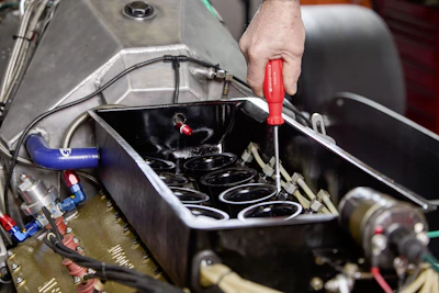 Mechanic using a screwdriver on car engine parts.