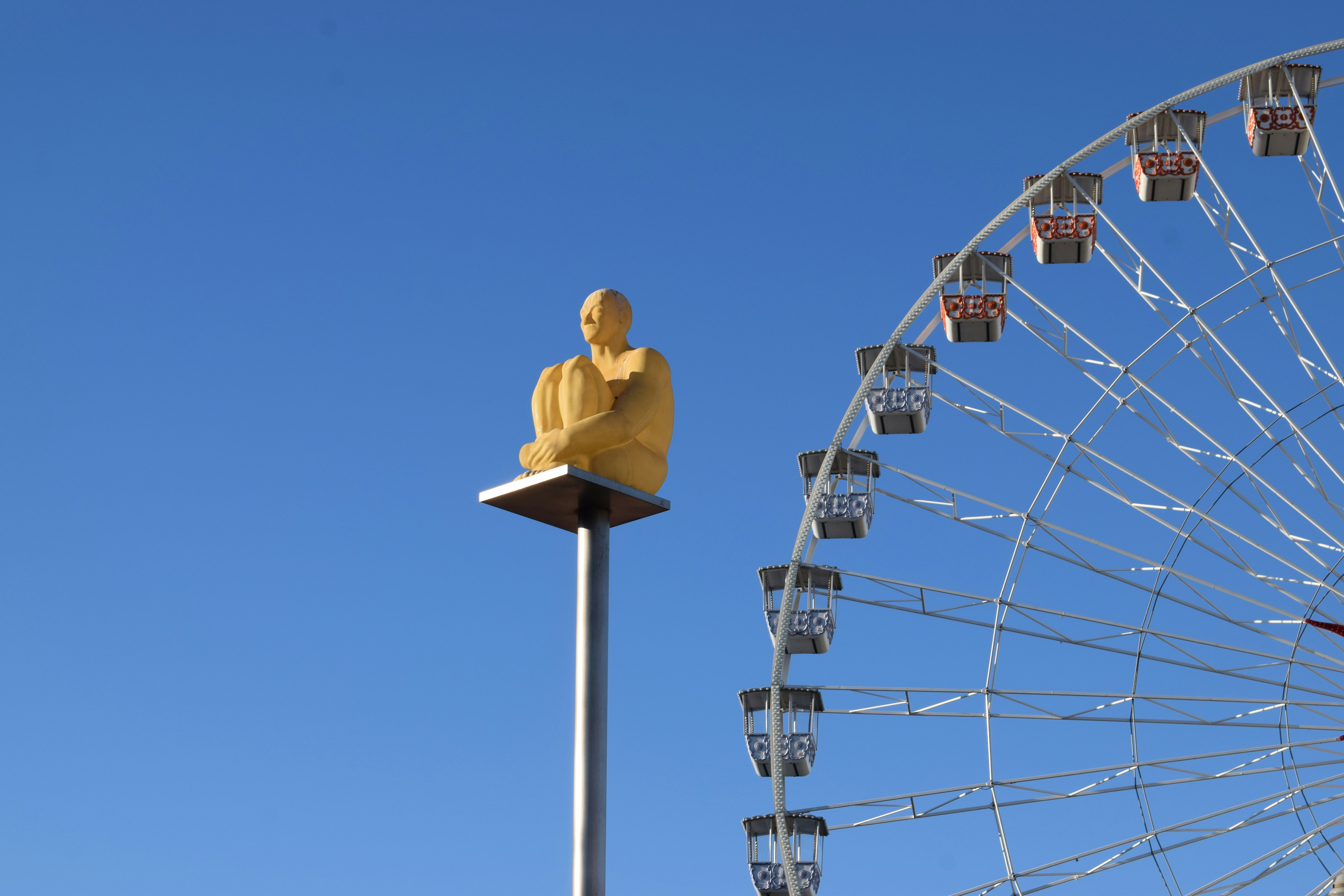 Golden statue sits on pole near ferris wheel