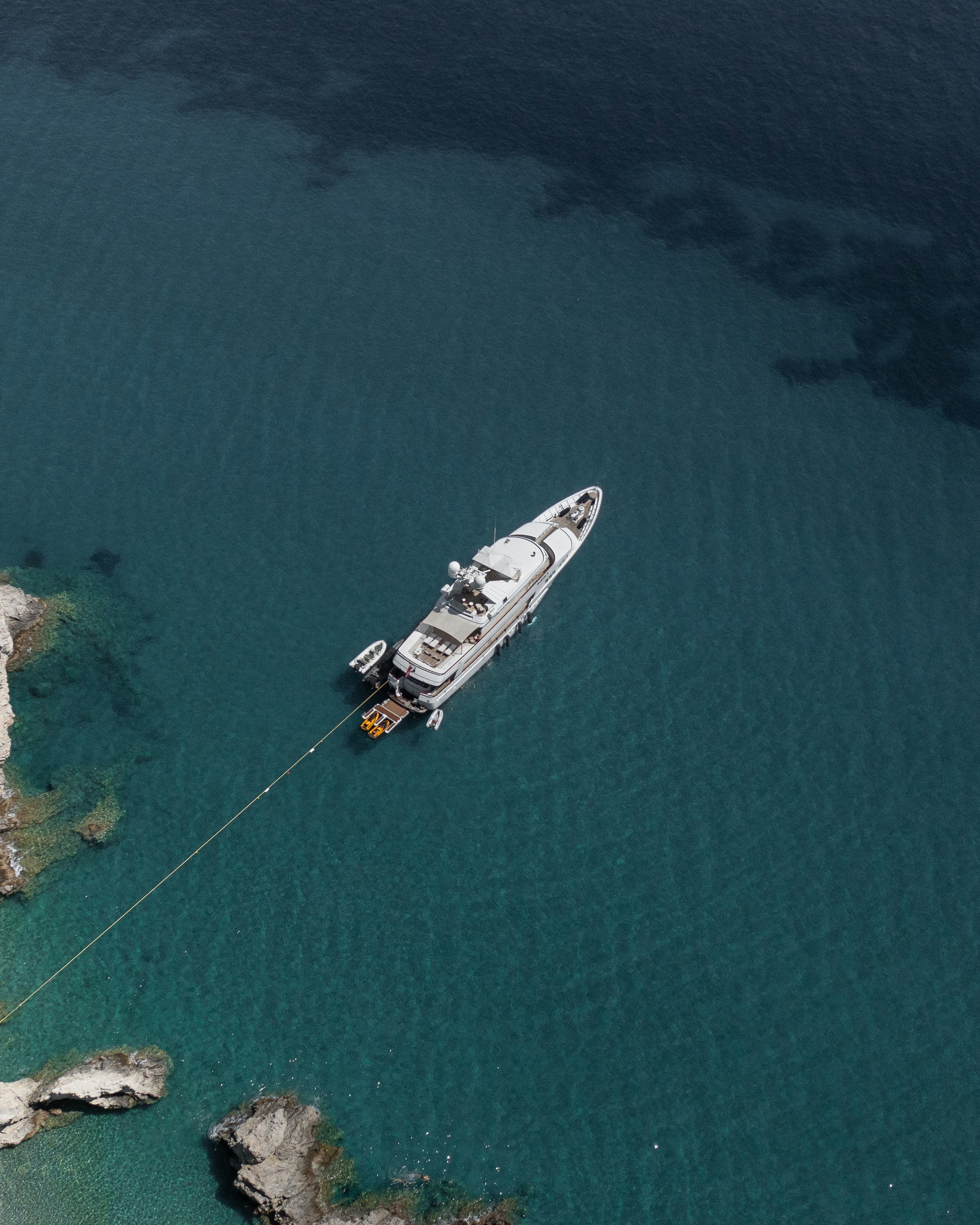 A large yacht anchored in clear blue ocean water.