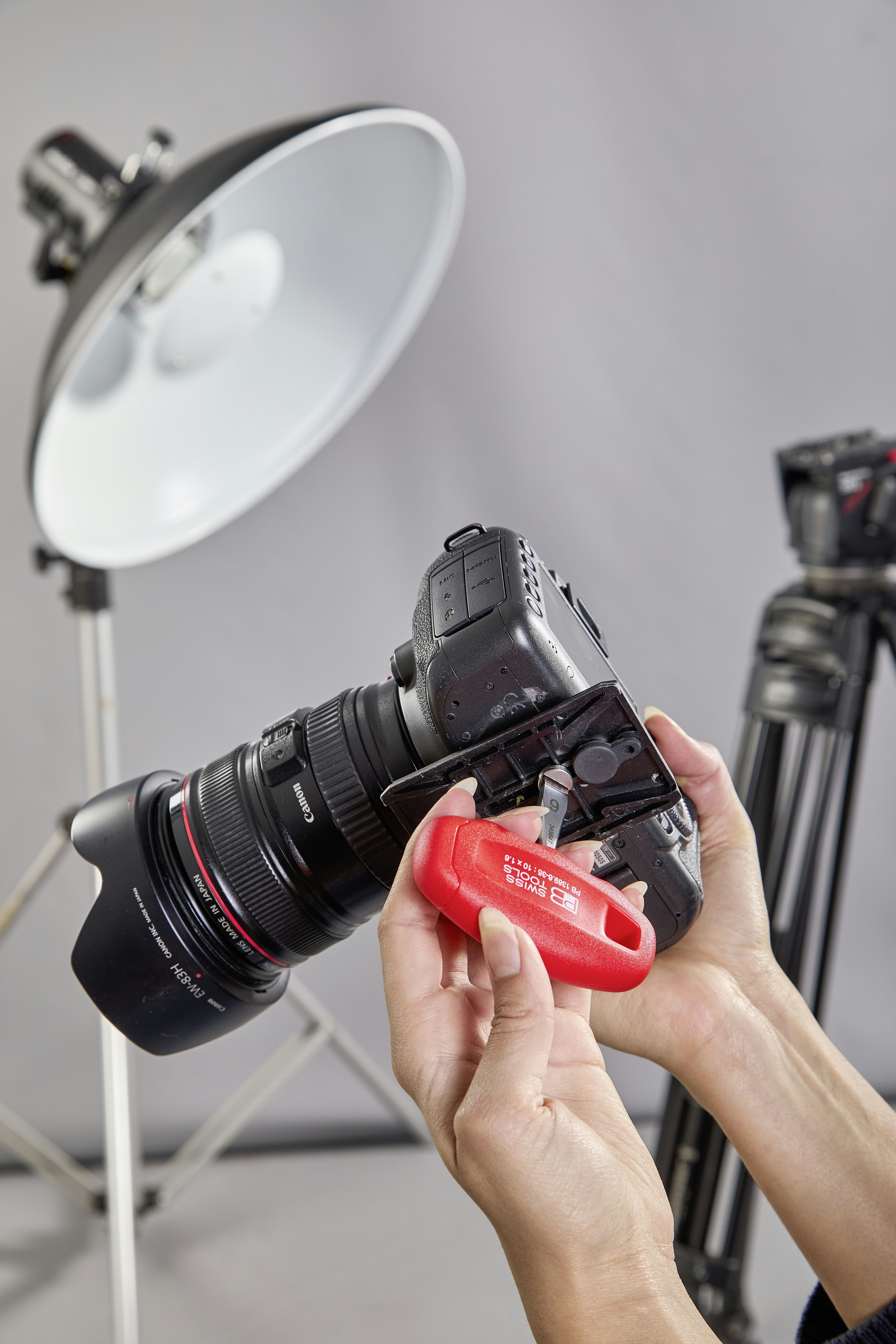 Hands adjusting a red camera accessory on a dslr camera.