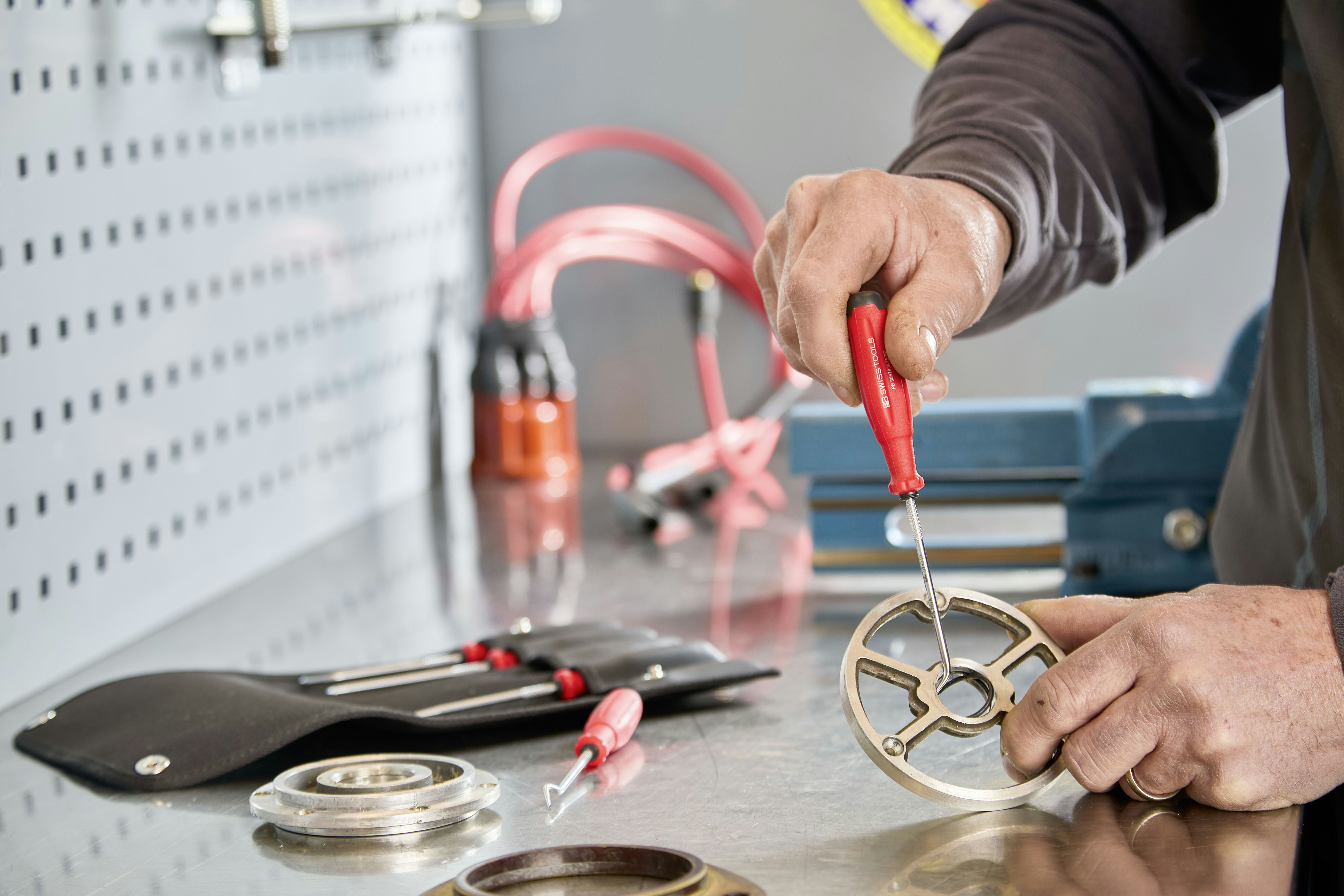 Mechanic working on a metal part with tools.