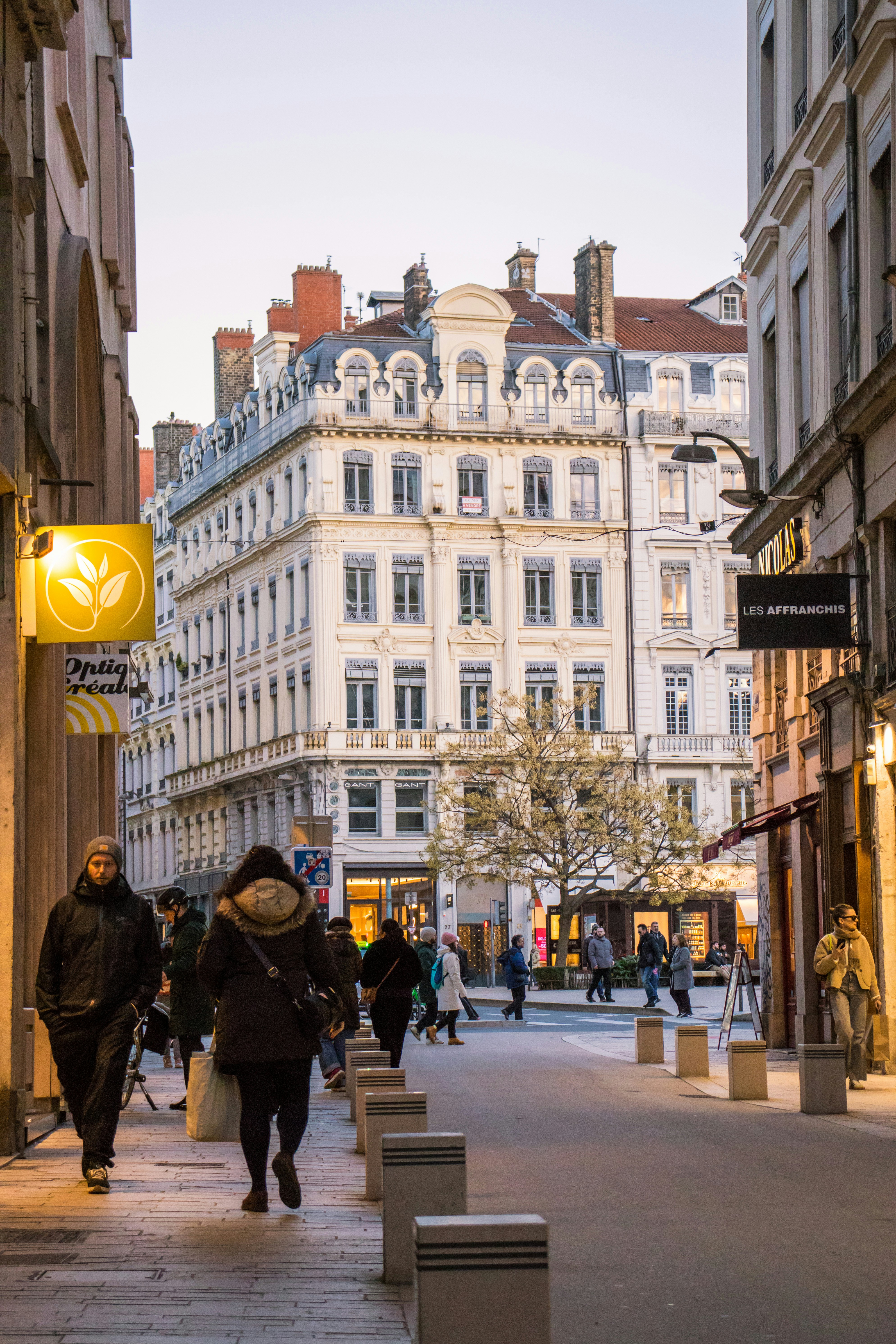 People walking down a european street with buildings.