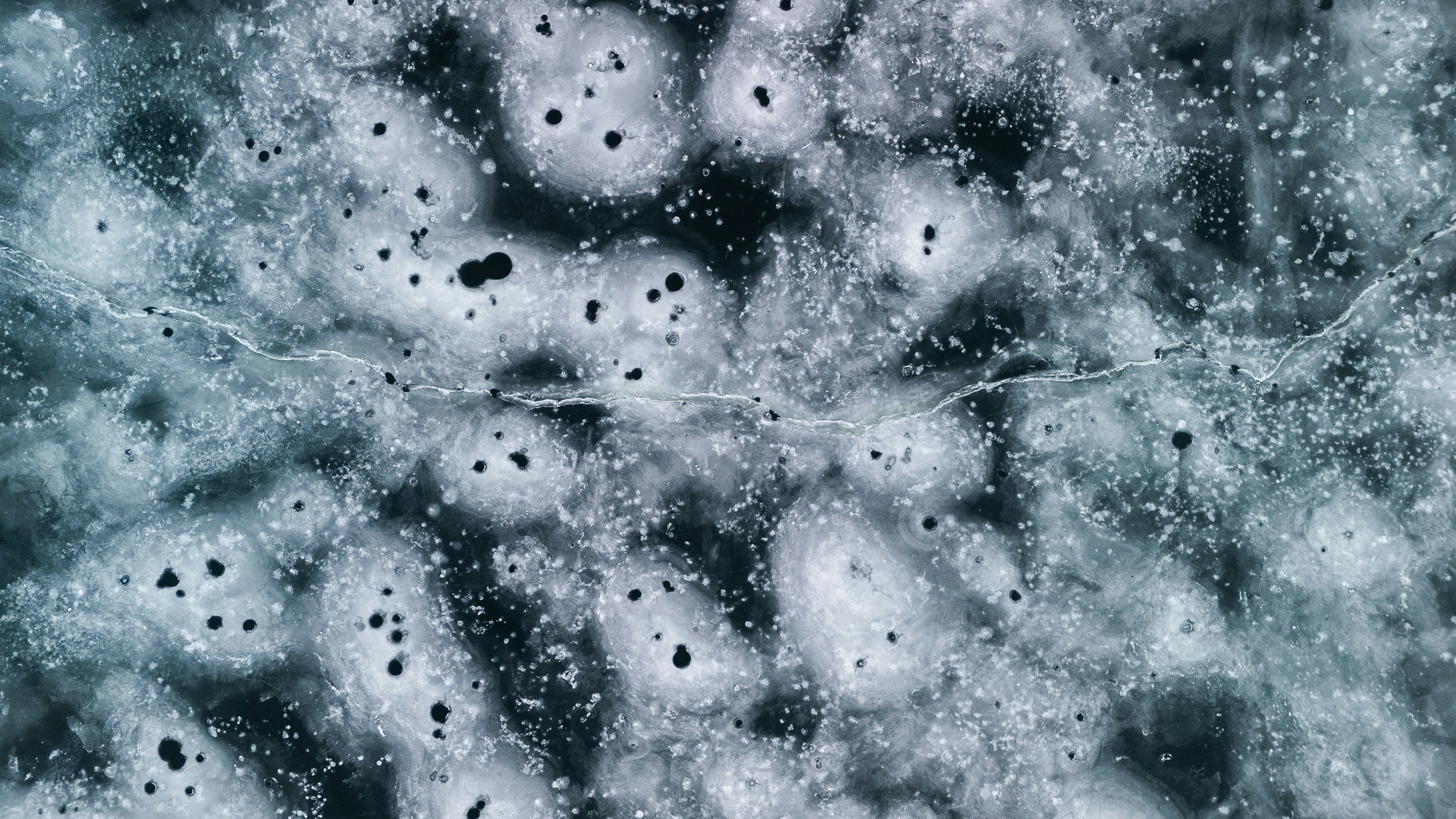 Abstract pattern of ice with dark circular inclusions