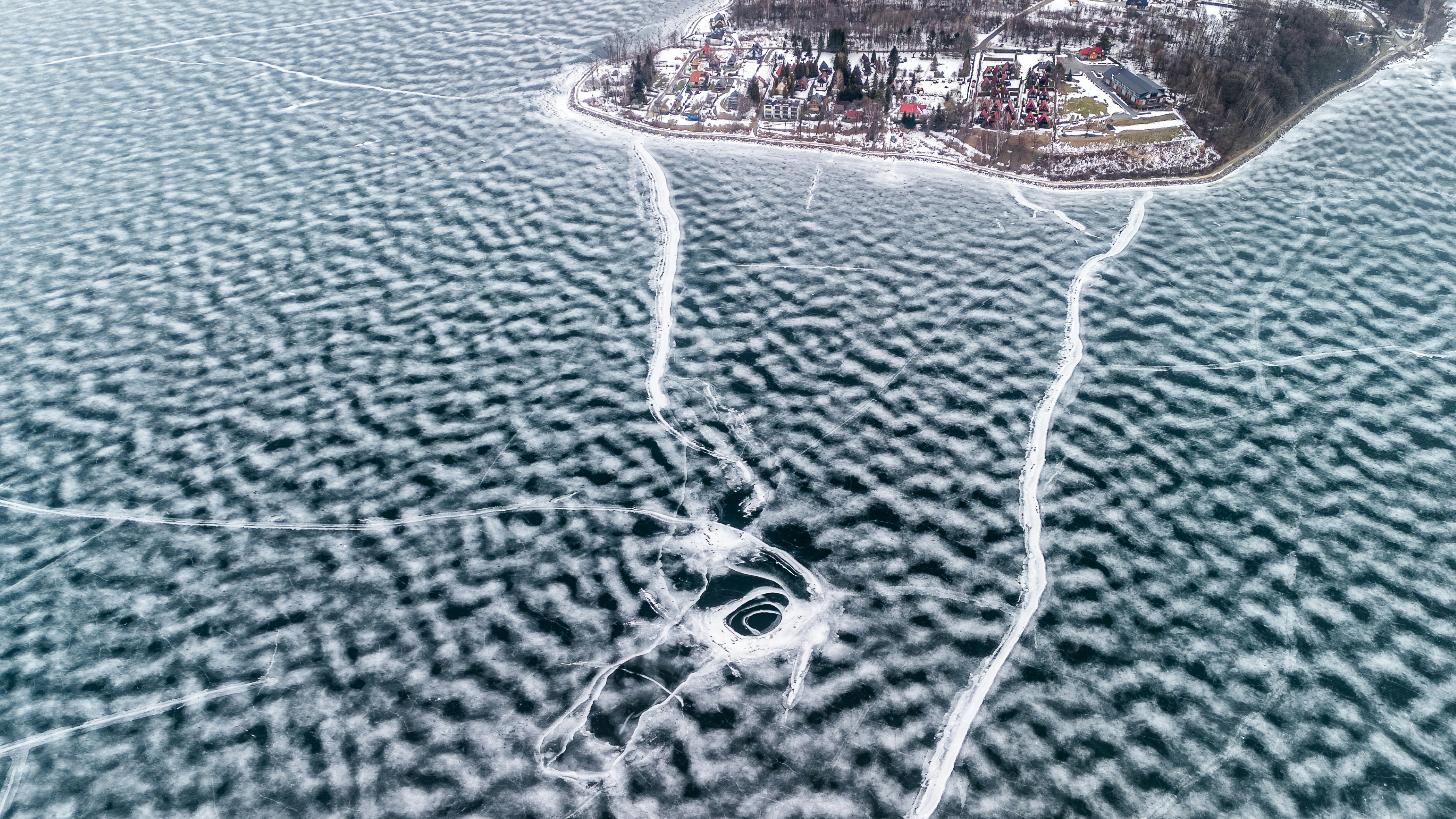 Lac gelé avec des motifs de glace et des bâtiments éloignés