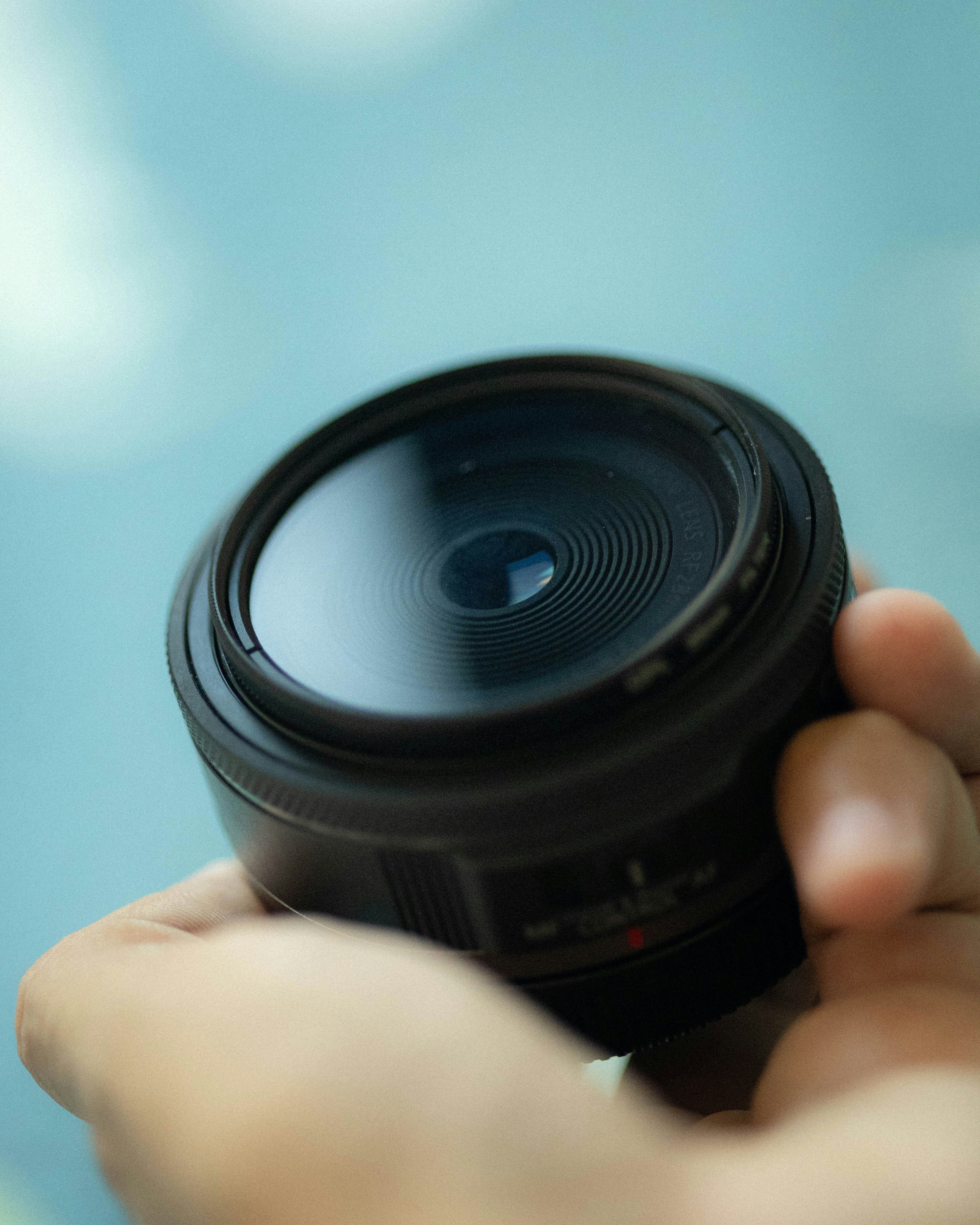 A hand holding a camera lens