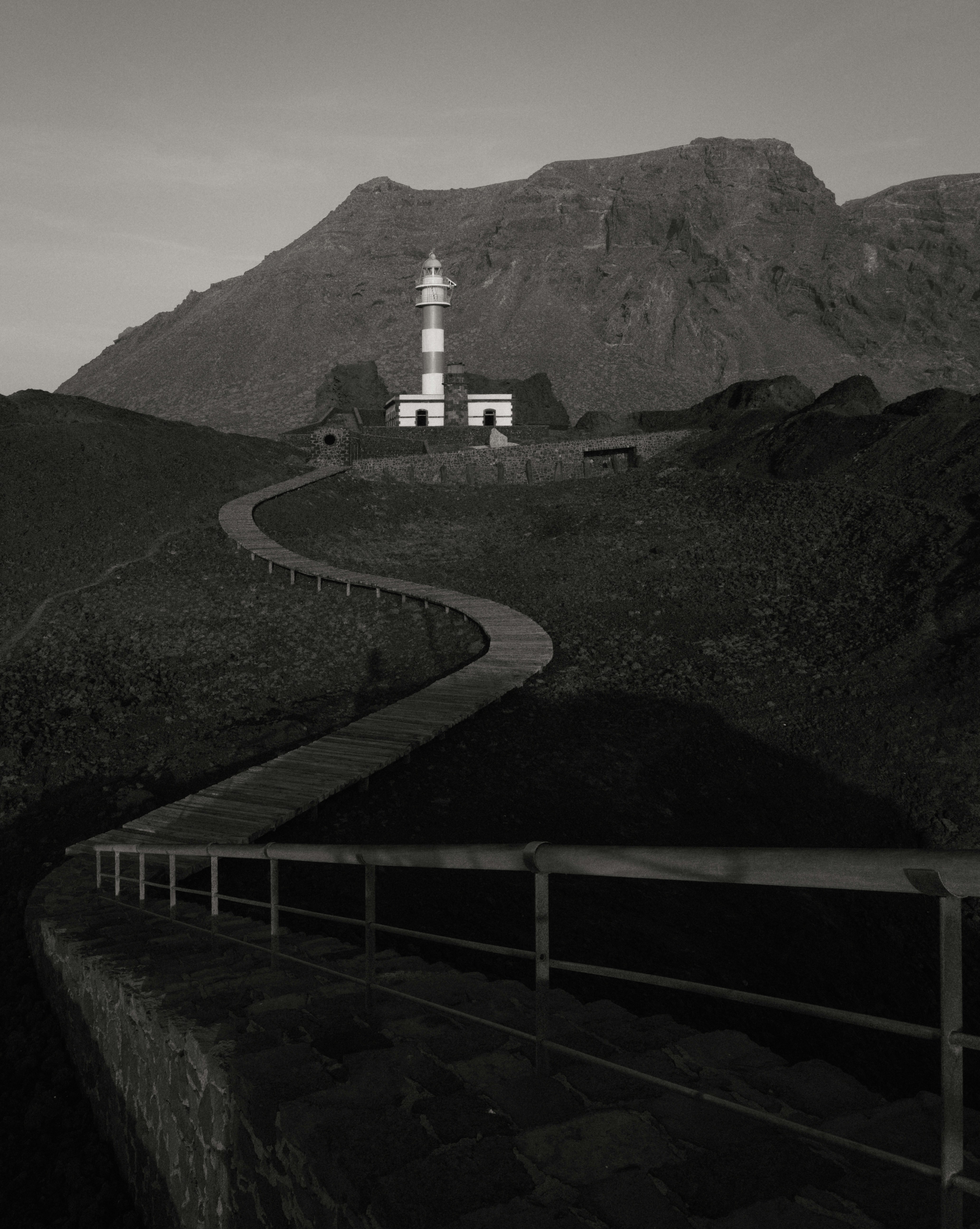 A winding path leads to a lighthouse on a hill.