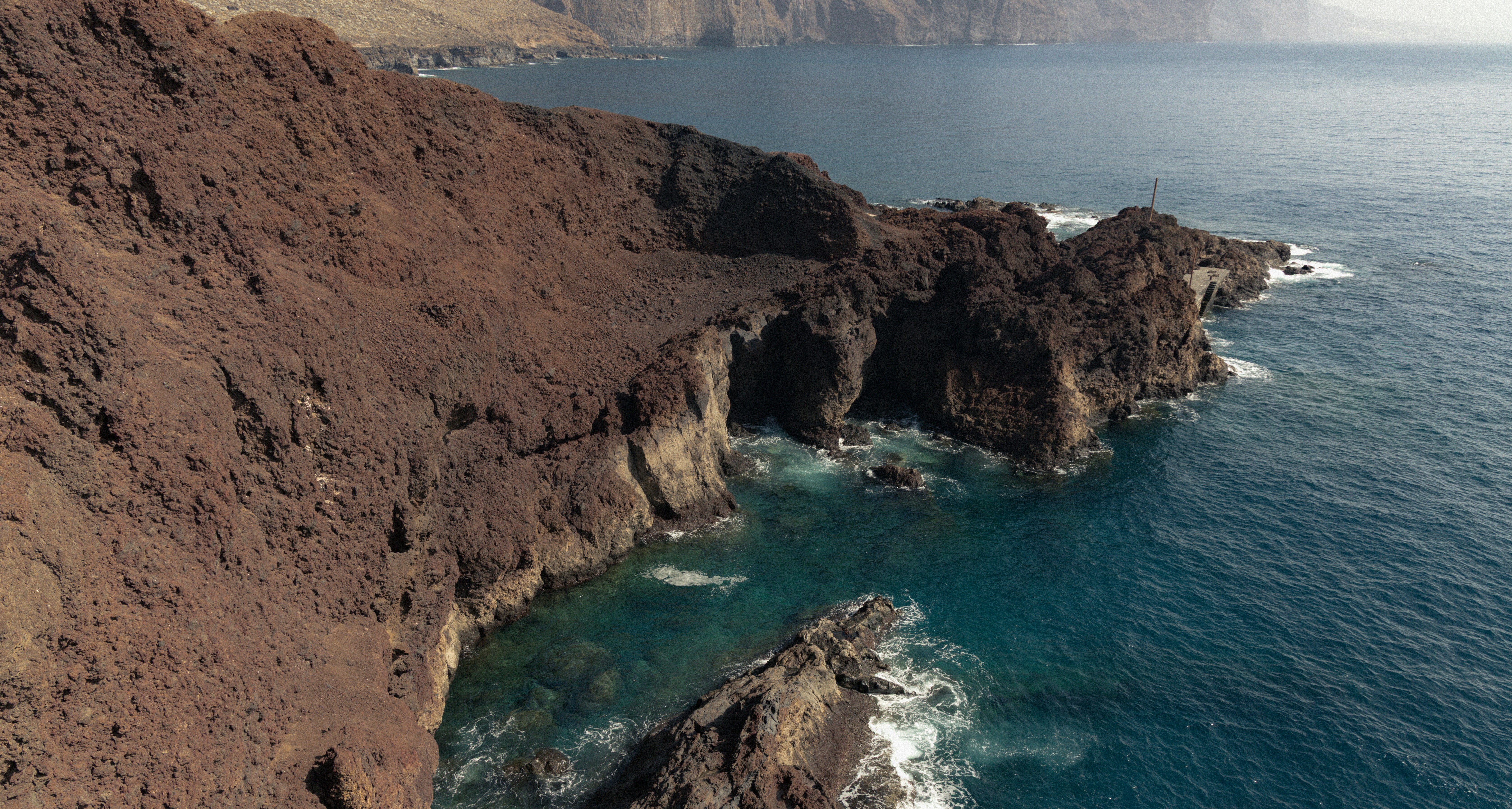 Rocky coastline with waves crashing against cliffs.