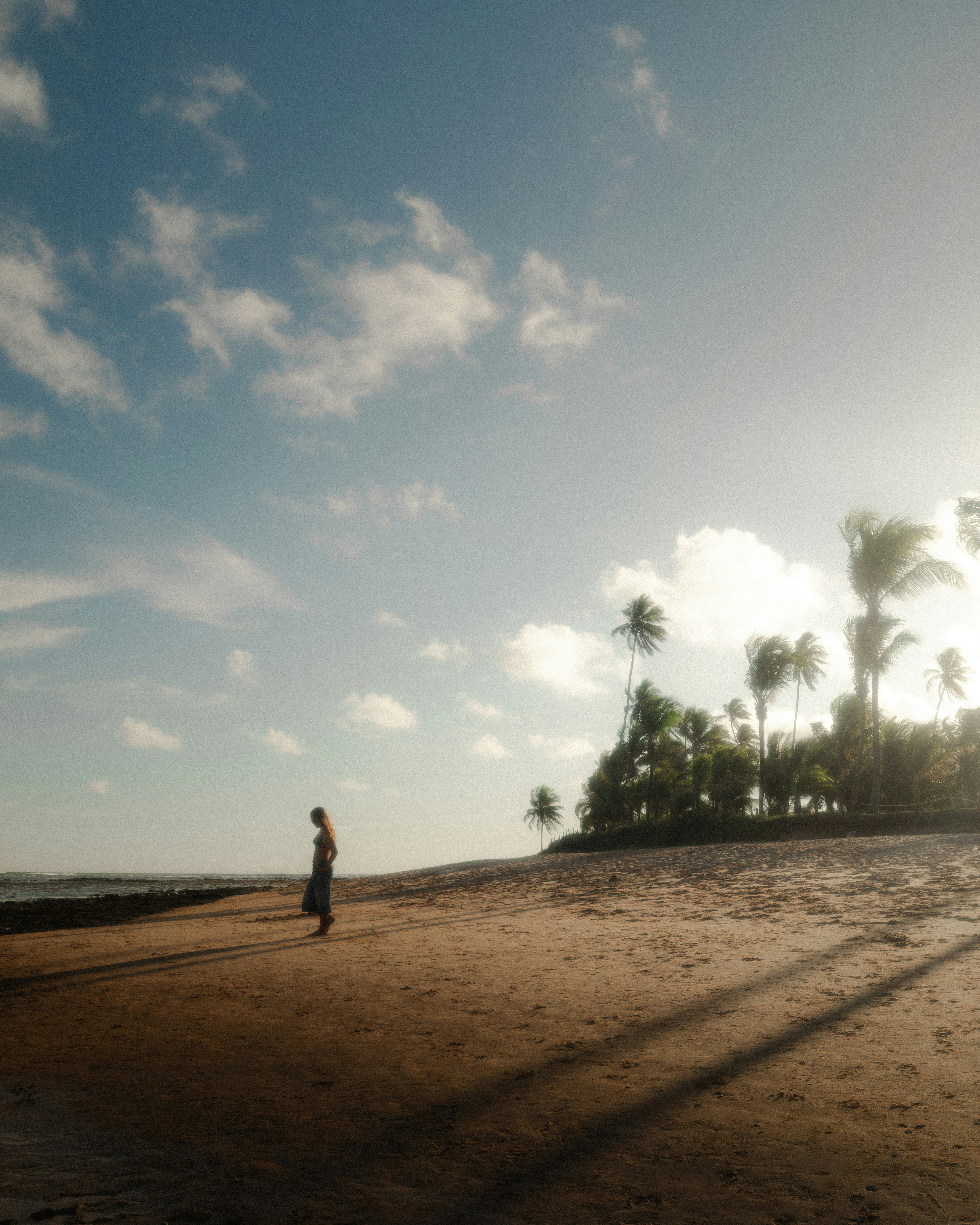 Woman walking on a sandy beach at sunset