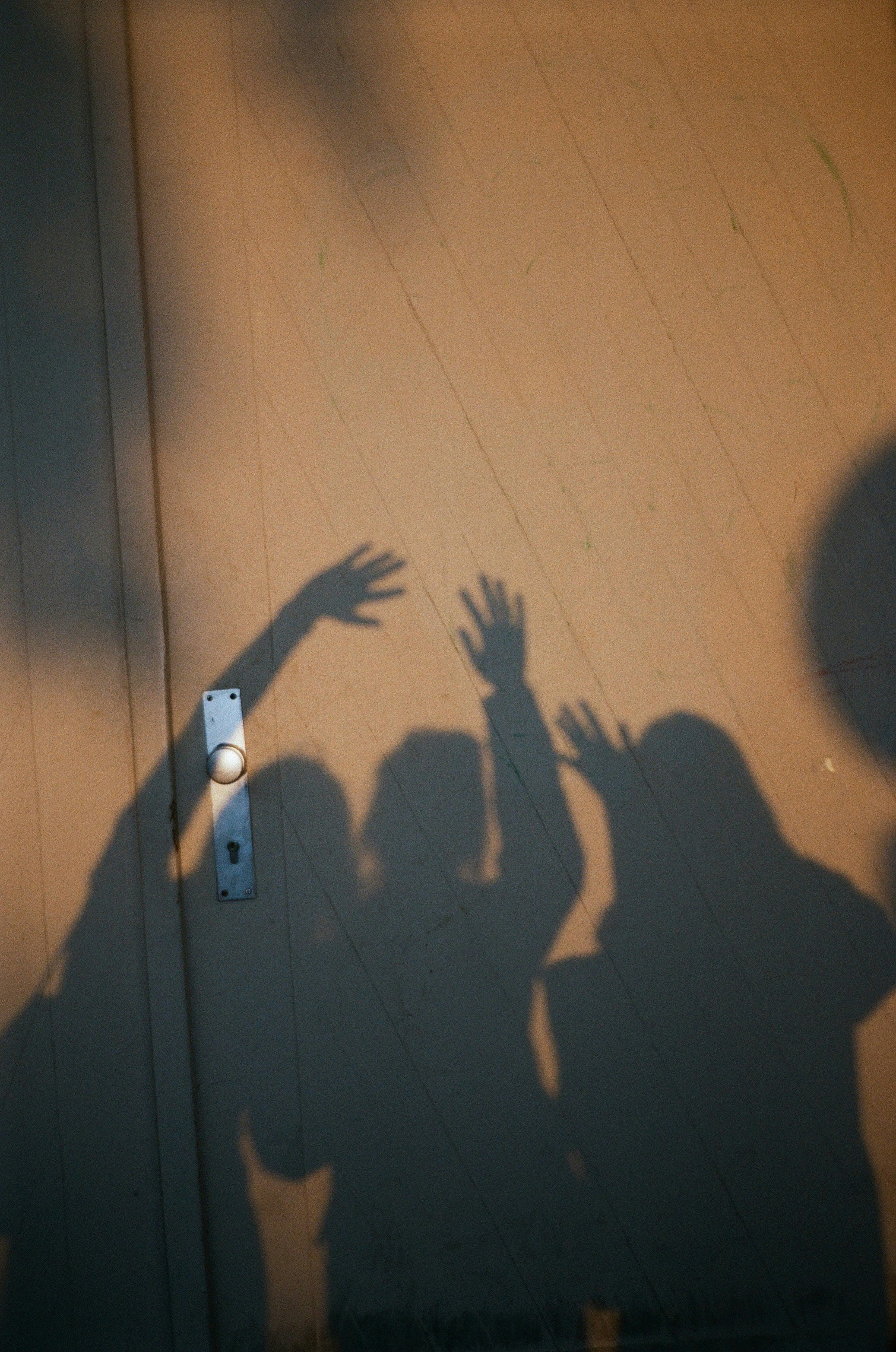 Shadows of three people with raised hands on a wall