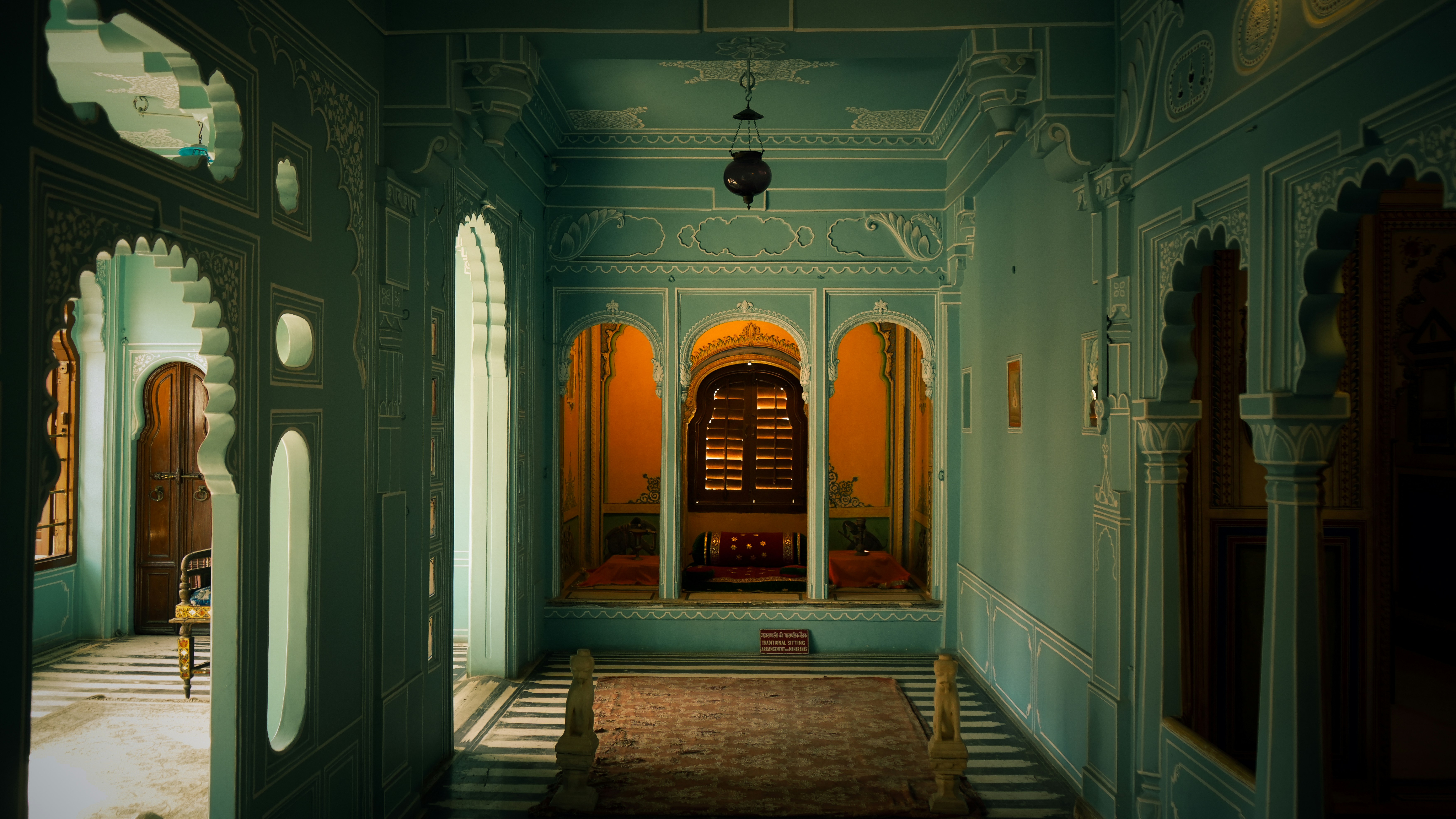 Ornate turquoise hallway with arched doorways and intricate details