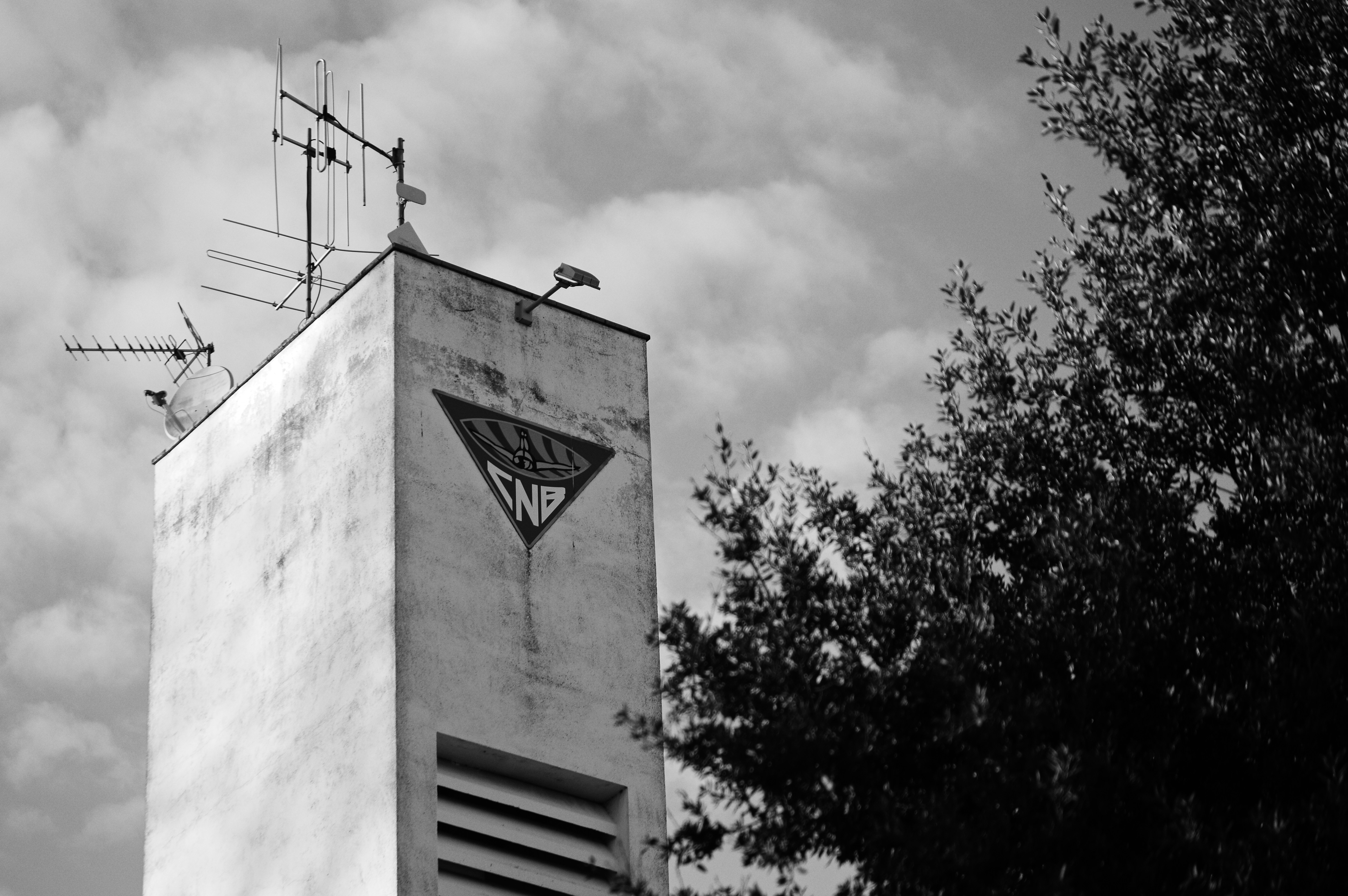 A tall, weathered tower with antennas and a triangle symbol.