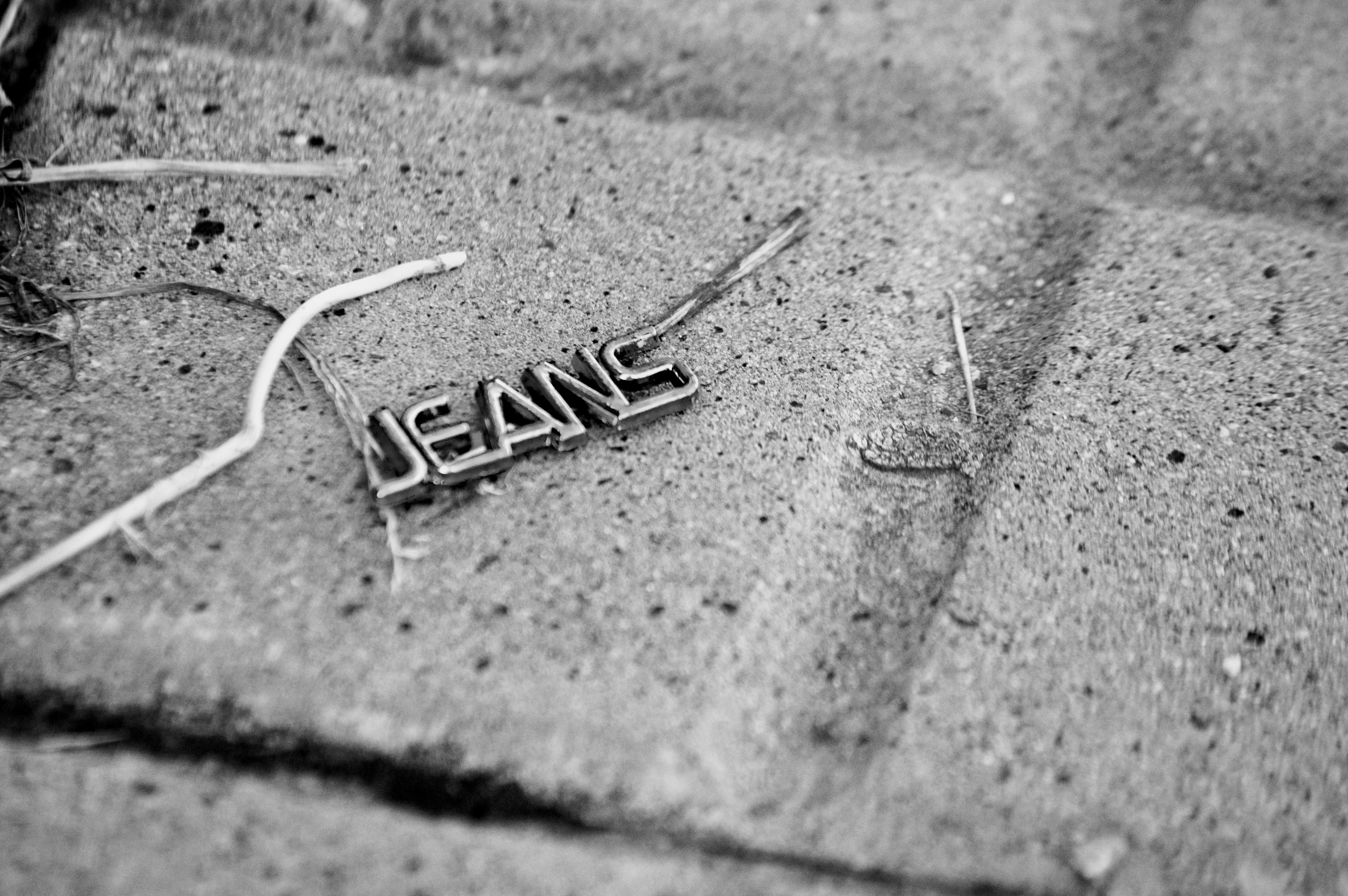 Metal word jeans lying on textured ground.
