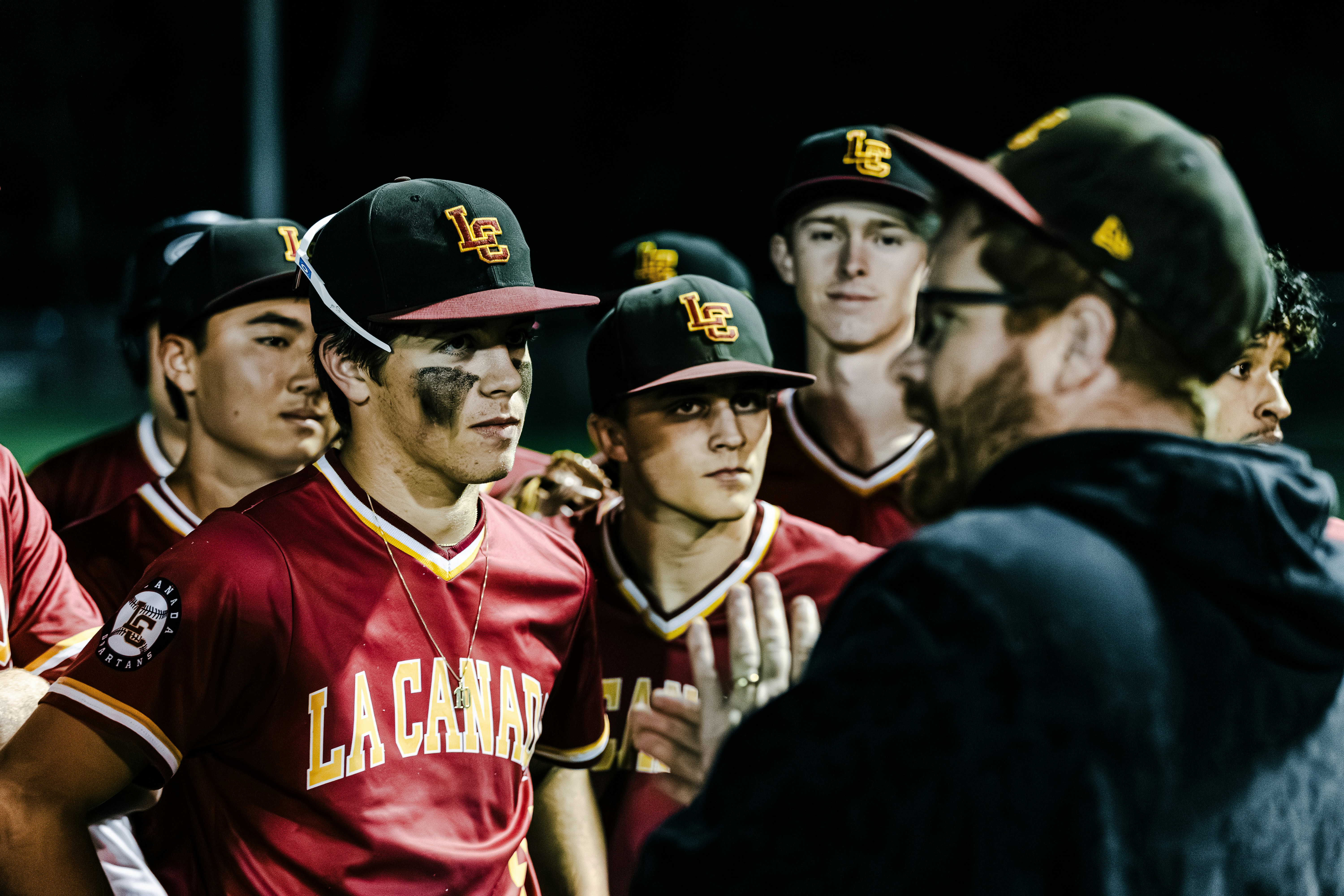 Baseball team huddles with coach during game