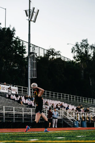 A female volleyball player serves the ball on a field