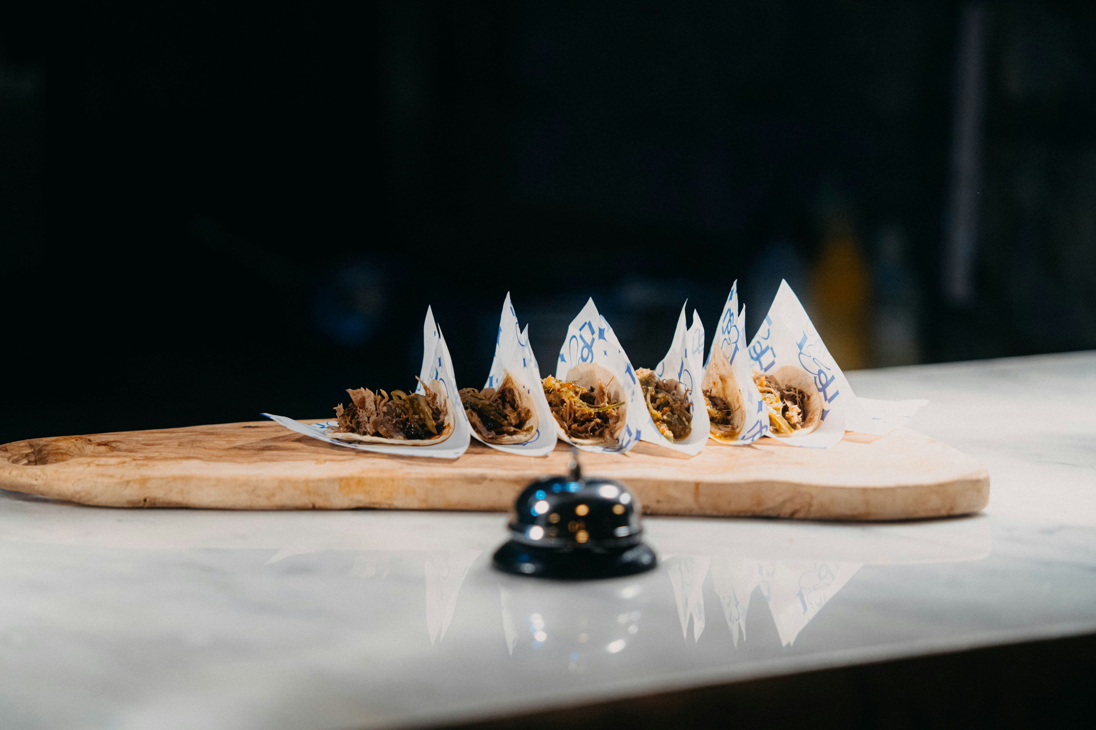 Kleine Vorspeisen, serviert auf einem Holzbrett mit einer Glocke.