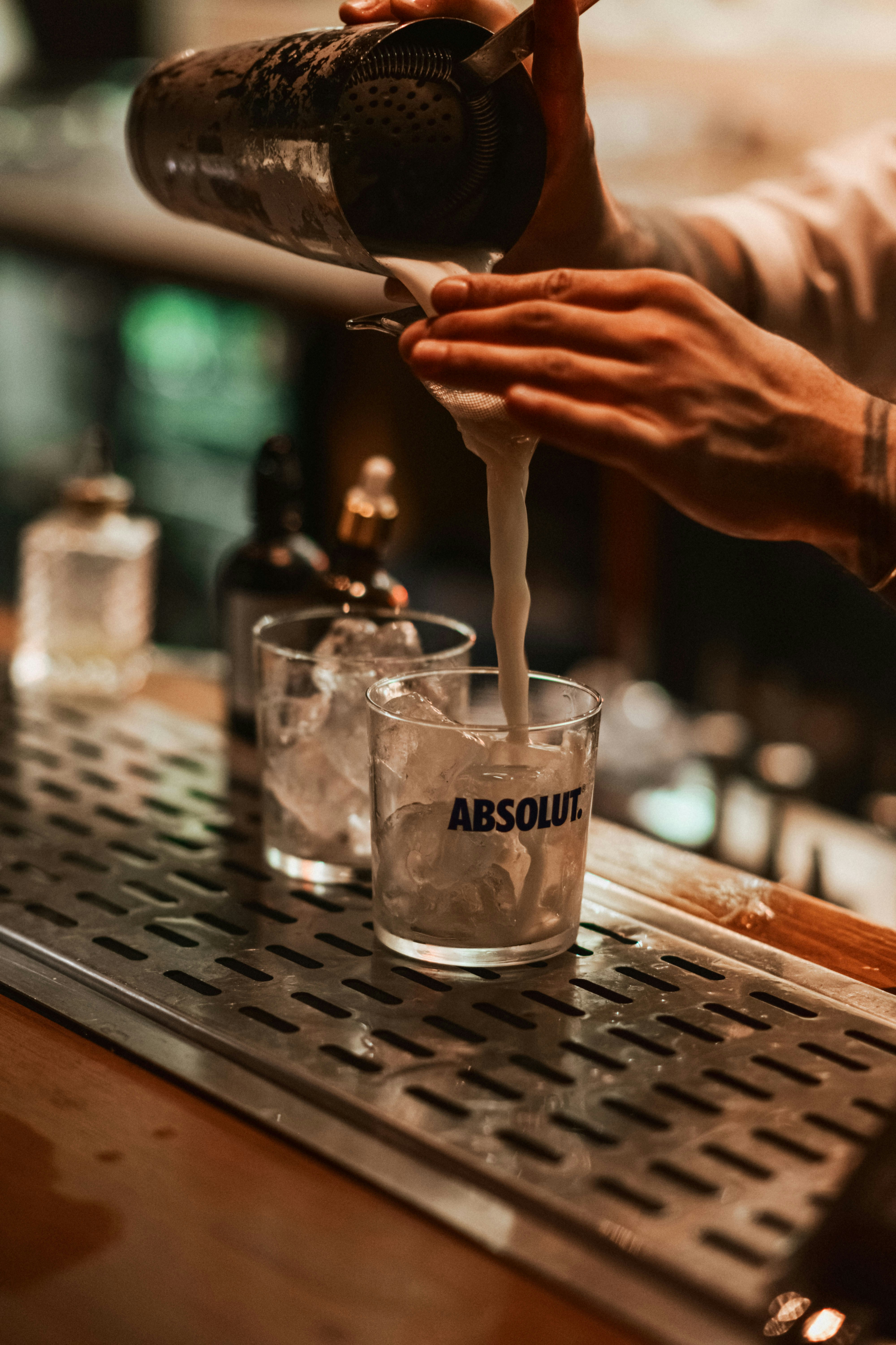 Barkeeper gießt einen Cocktail in ein Glas mit Eis.