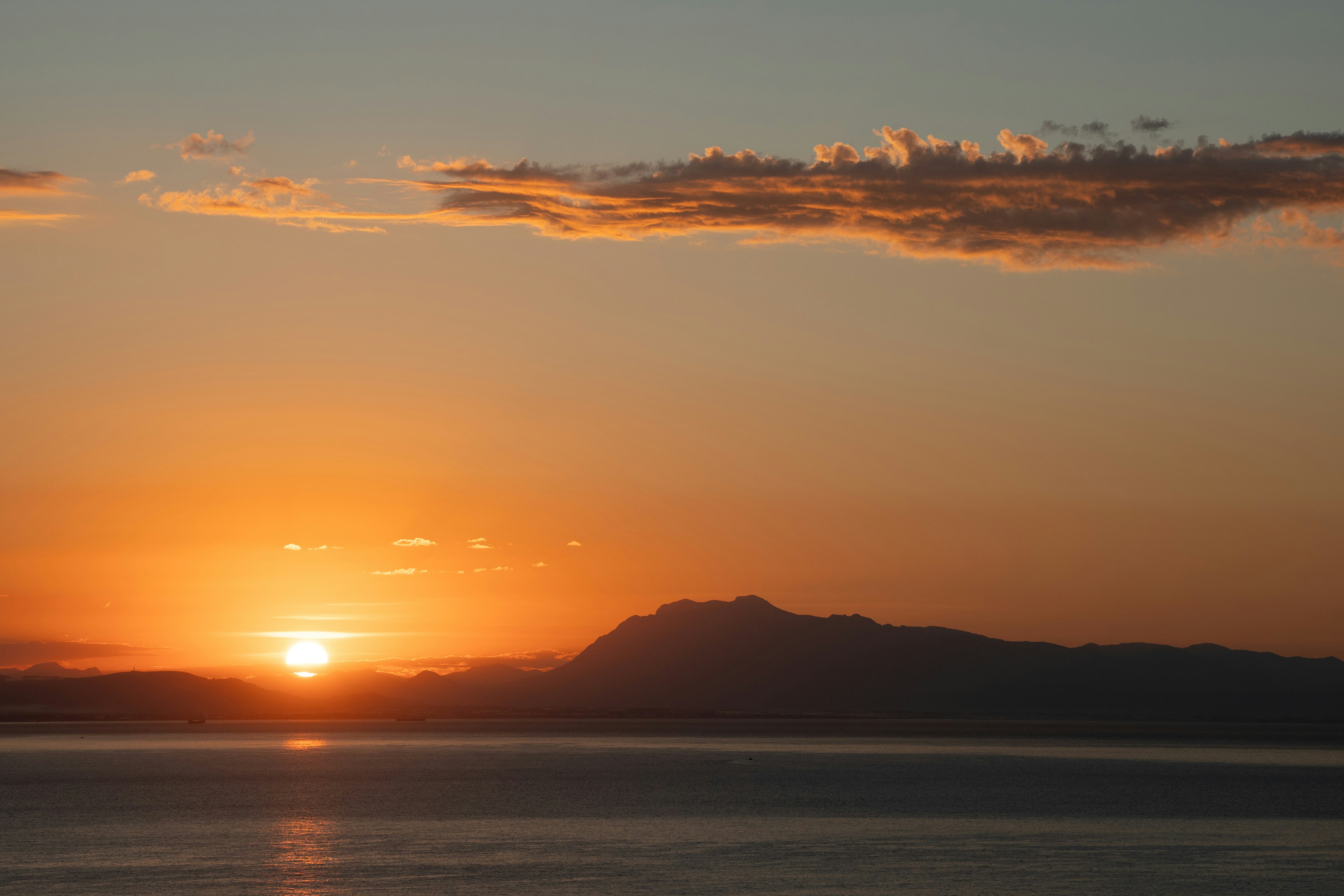 Sunset over the ocean with mountains in the distance