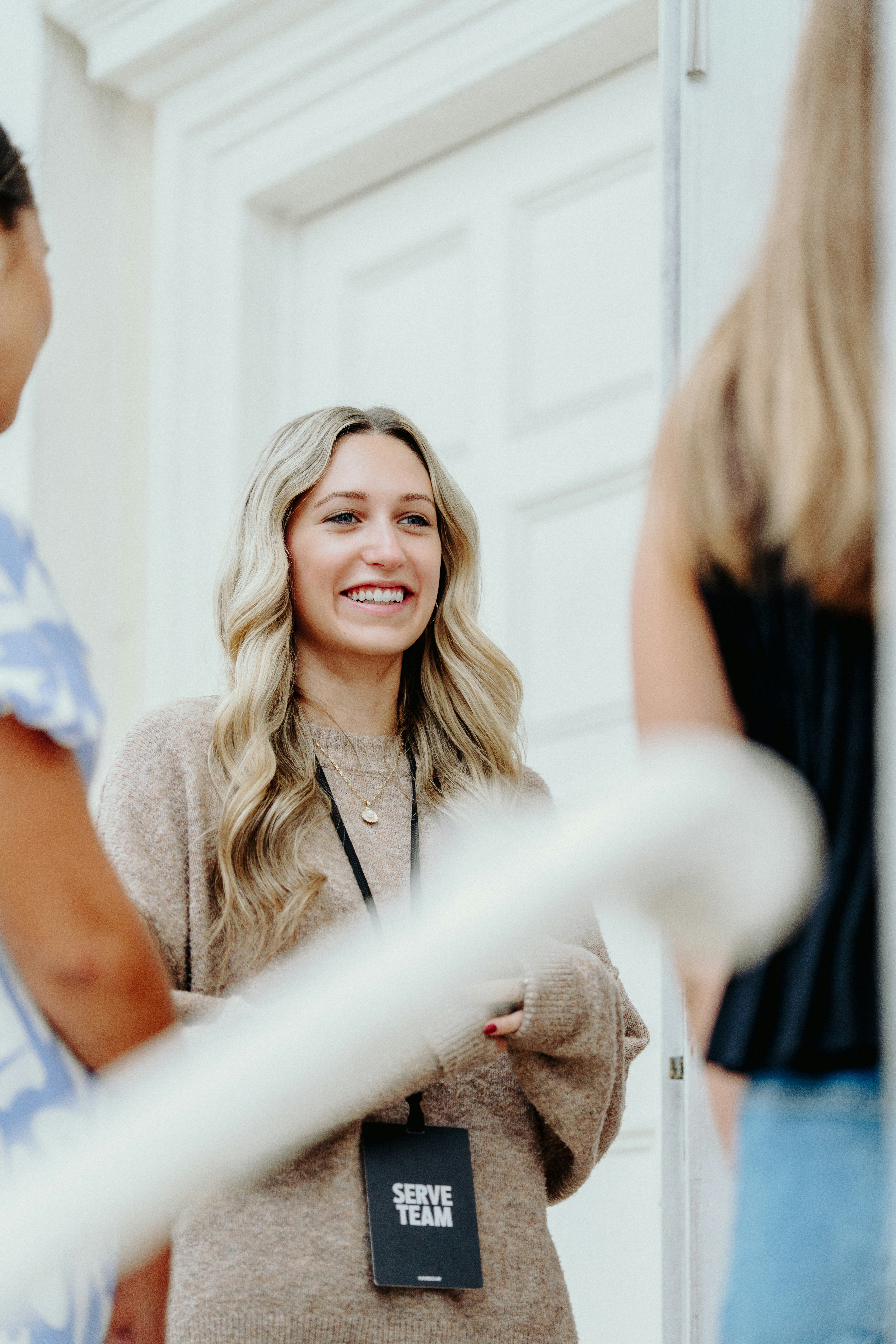 Una donna sorridente con i capelli biondi parla con gli altri.