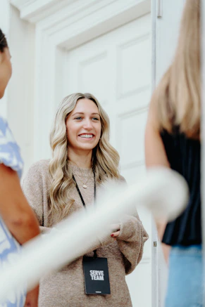 A smiling woman with blonde hair talks to others.