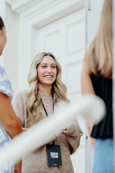 A smiling woman with blonde hair talks to others.