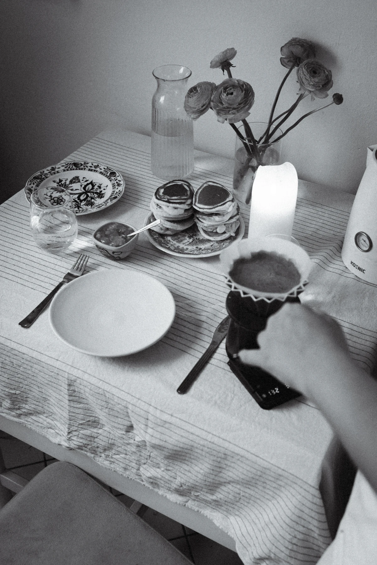 A bright breakfast table set with coffee and fresh flowers