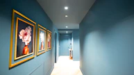 Hallway with blue walls and framed floral artwork.